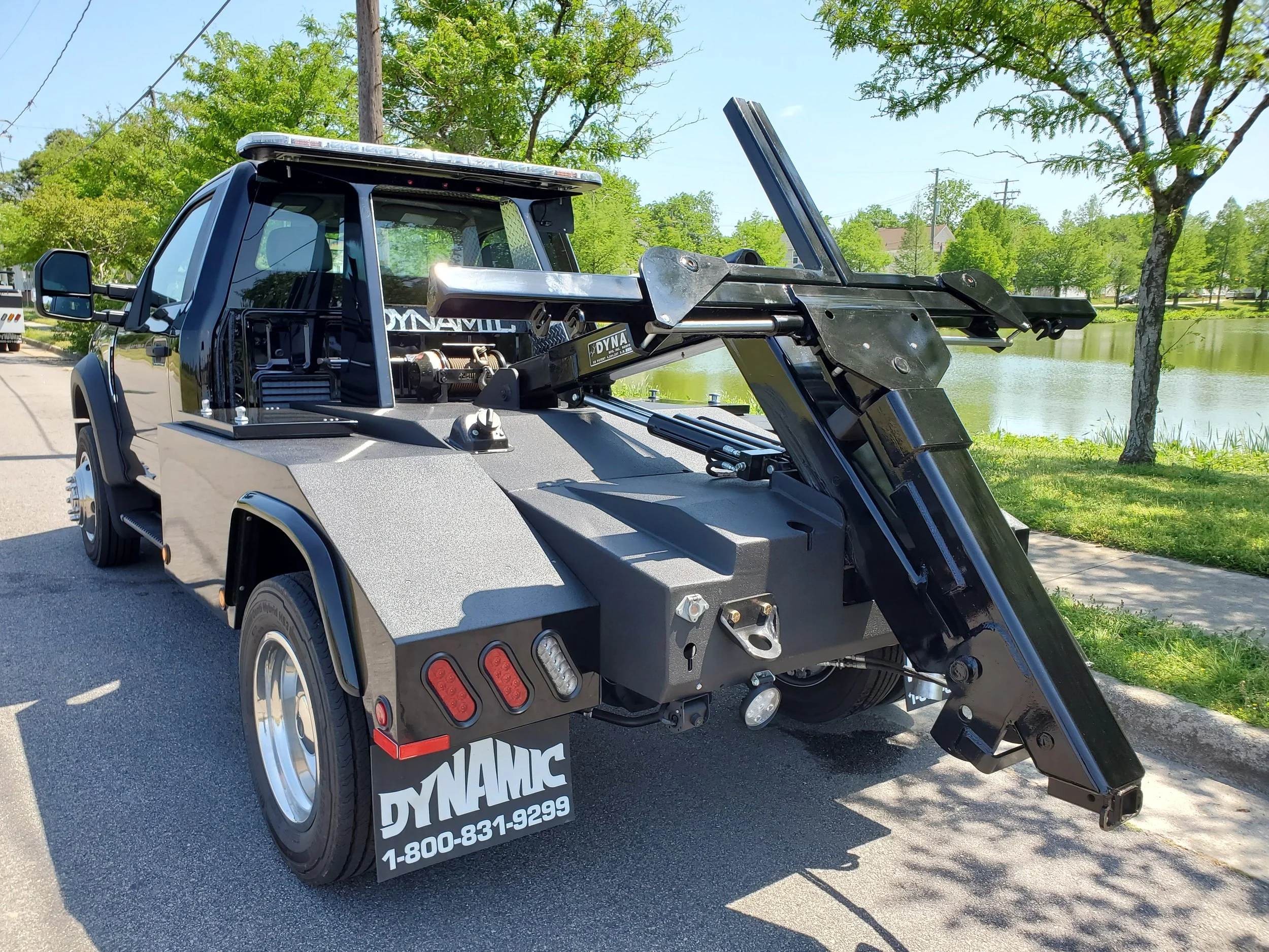 A black tow truck with a crane extends over the bed.
