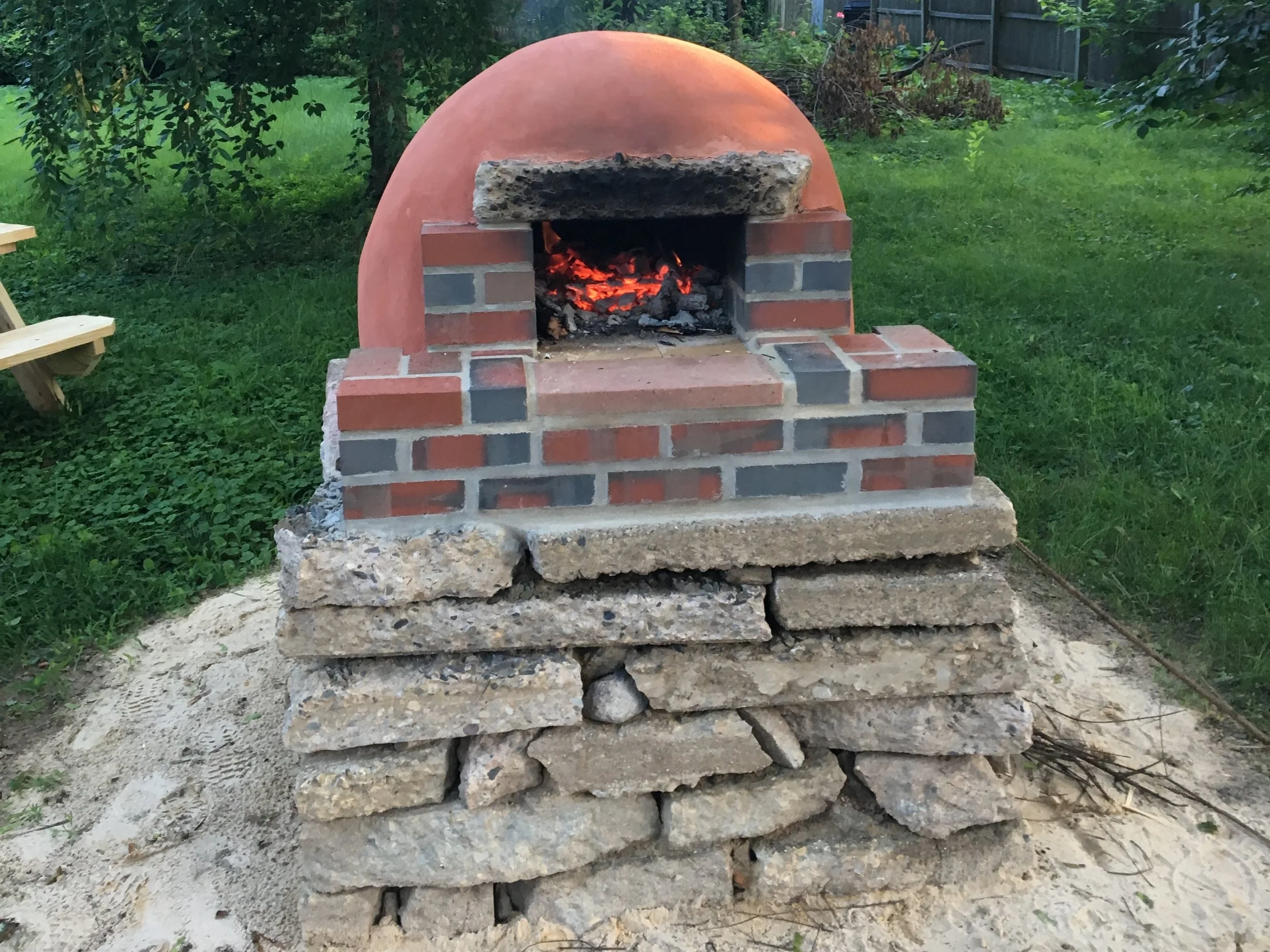 With a mind towards recycled materials, we used "urbanite" for the base of this clay/masonry hybrid oven. We found a few construction sites with busted up sidewalk, and with a little sweat we had ourselves a free and durable base. 