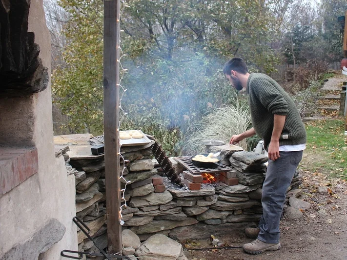 The stone wall next to this oven ties in the stone from the oven, creates counterspace, creates a grill spot (for boiling bagels!), and defines the edge the of yard. 