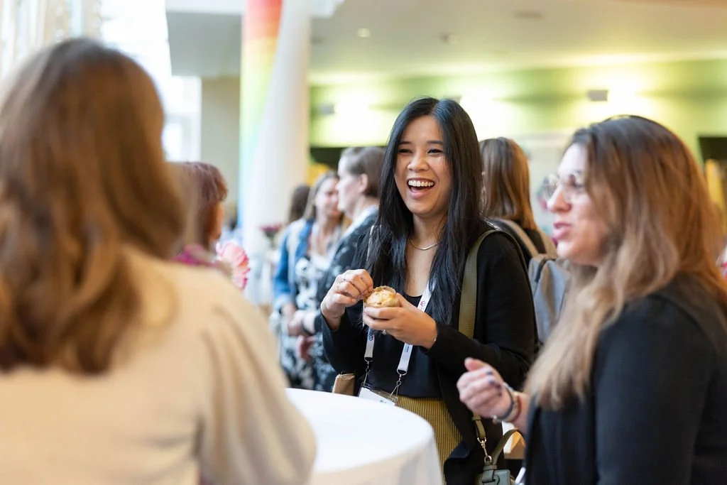 Conference attendee smiling and conversing with other attendees