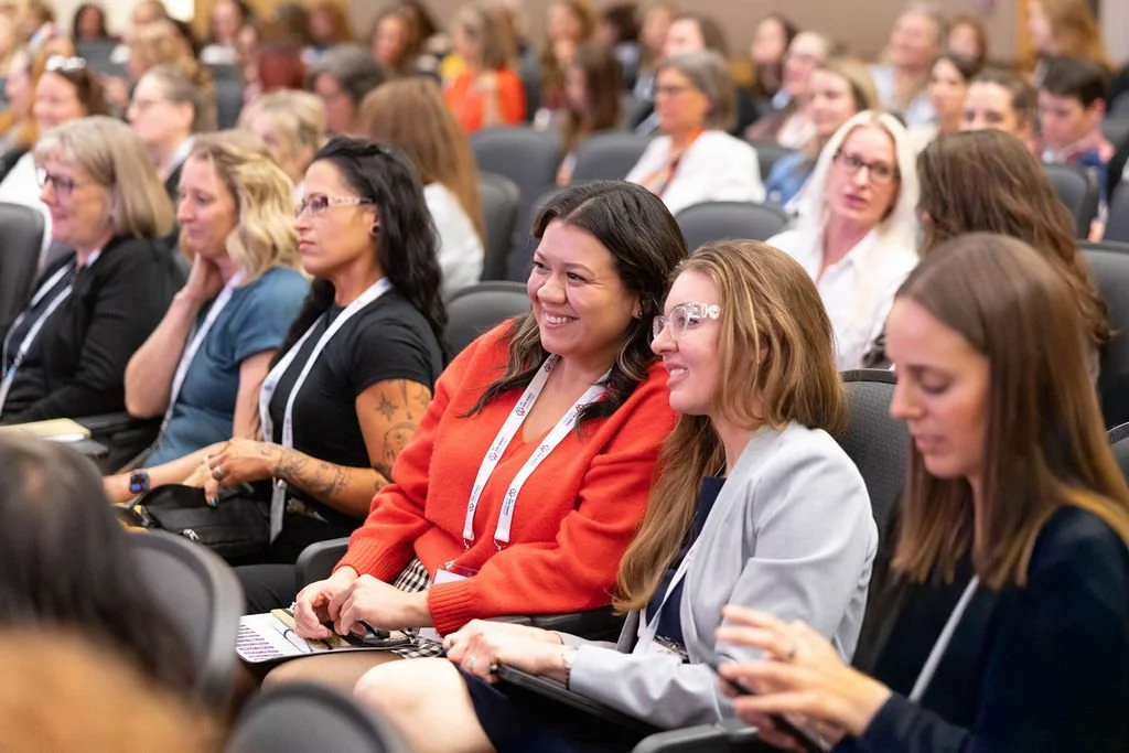Conference attendees listening to a keynote speaker and smiling