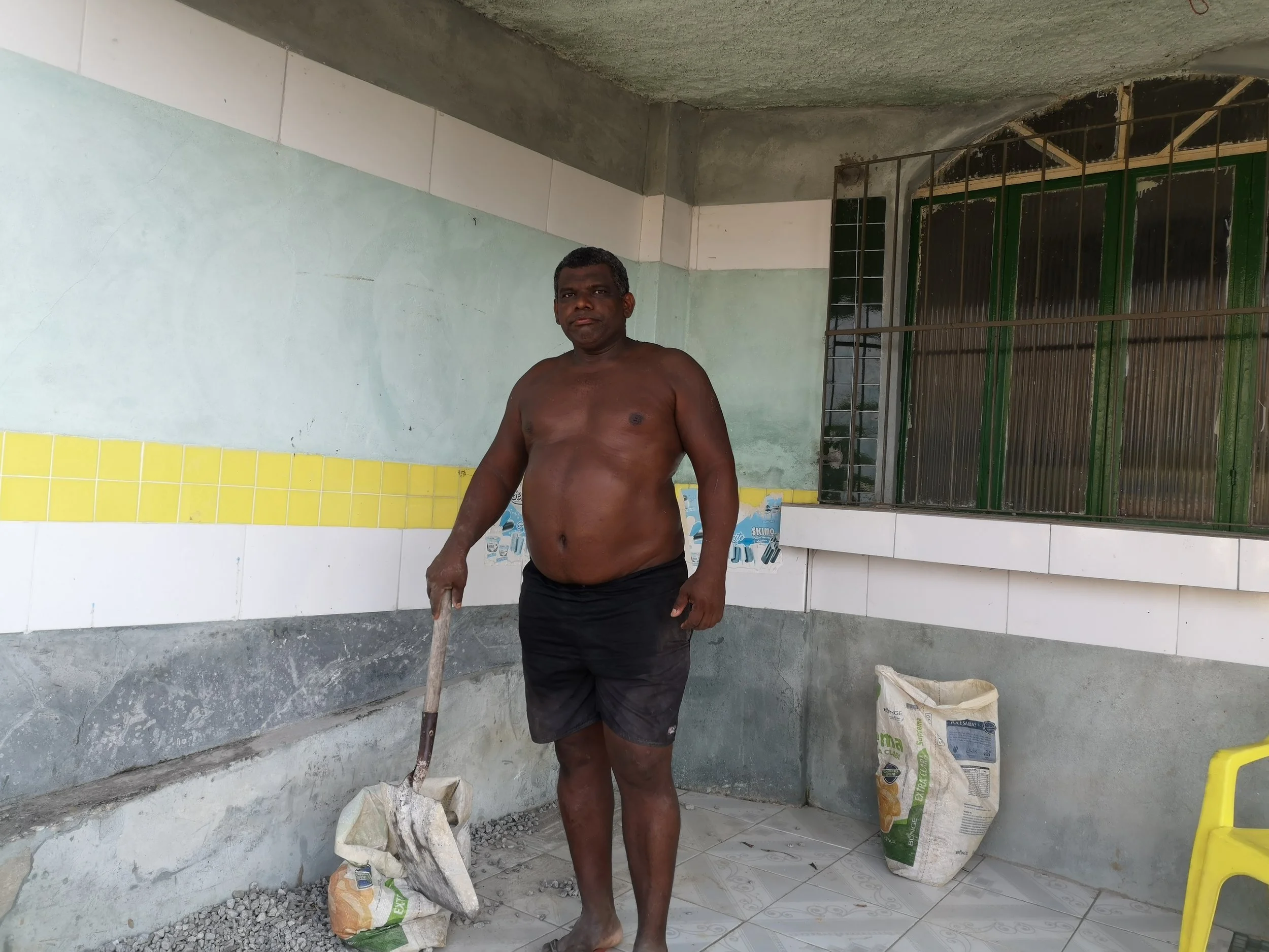 Neighbor Elias, on the porch of his house, designing his terrace with left-over tiles
