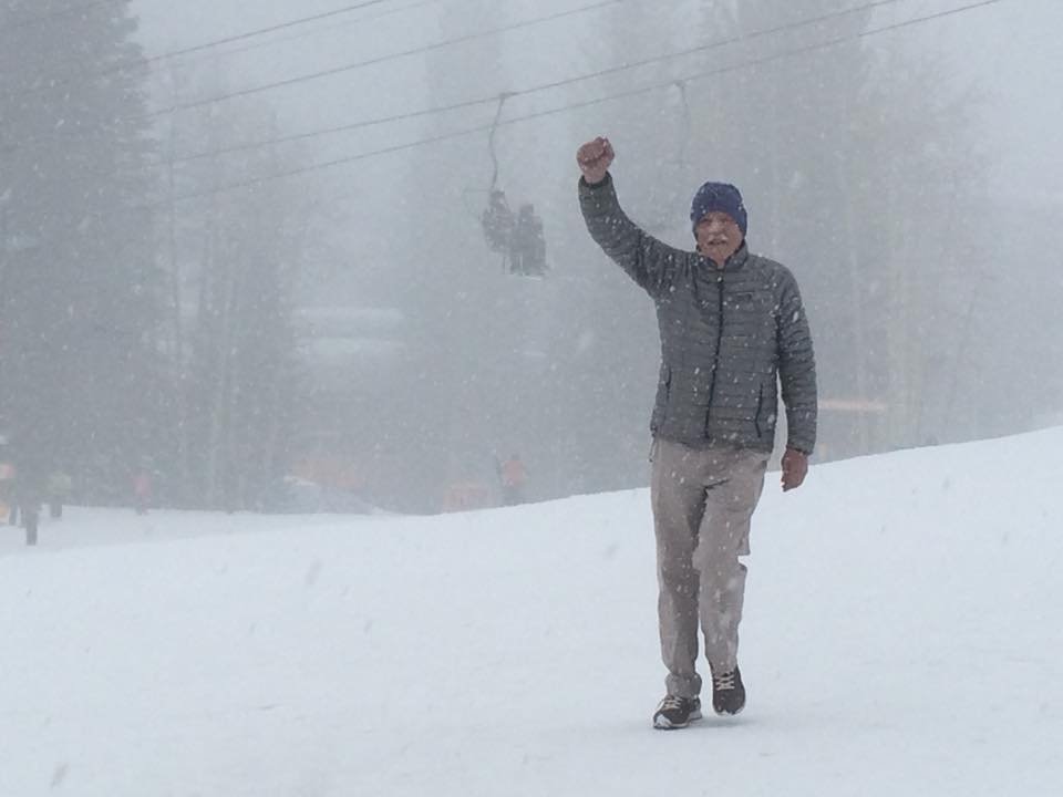 Holly walking down a ski slope in a snowstorm, fist raised