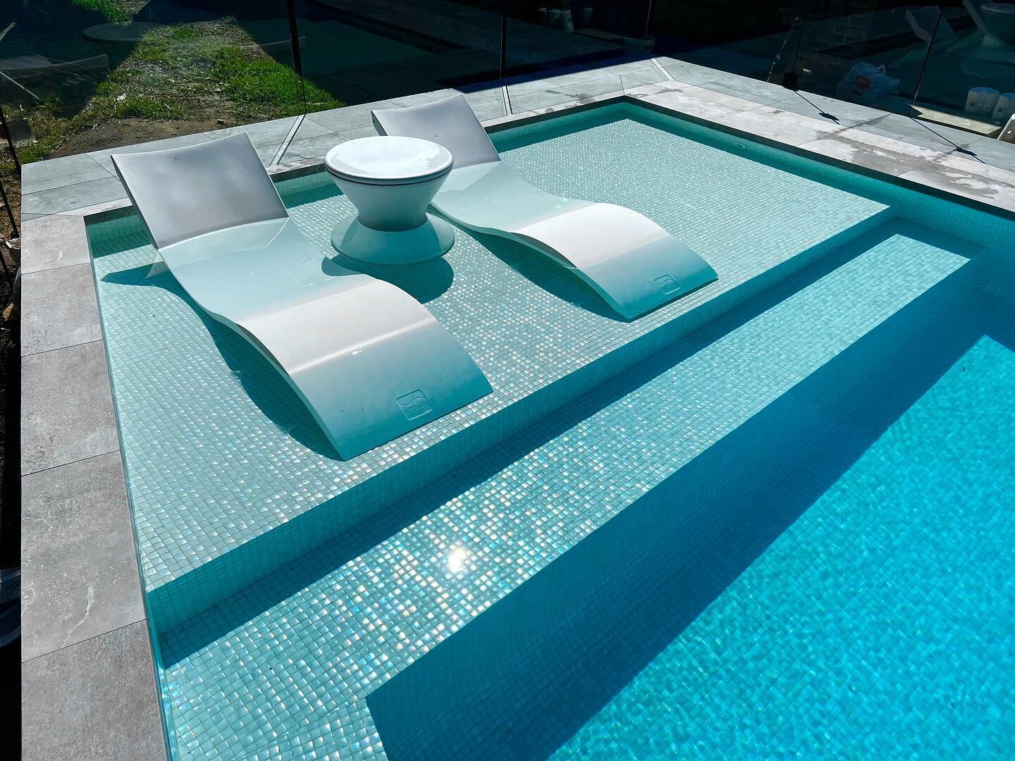 A last blast of sunshine before another week of rain. Ledge Lounger Chaise and Ice Bin side table in a shallow beach area. Whitehaven Sand mosaic tiles from @artisanexterior_