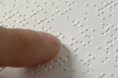 A single finger resting on a line of braille.
