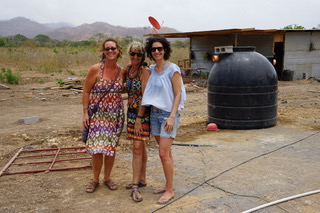 Standing in front of the water tank. All of the water necessary for construction must be trucked in and stored. The completed resource center will feature a community well and drinking fountain.