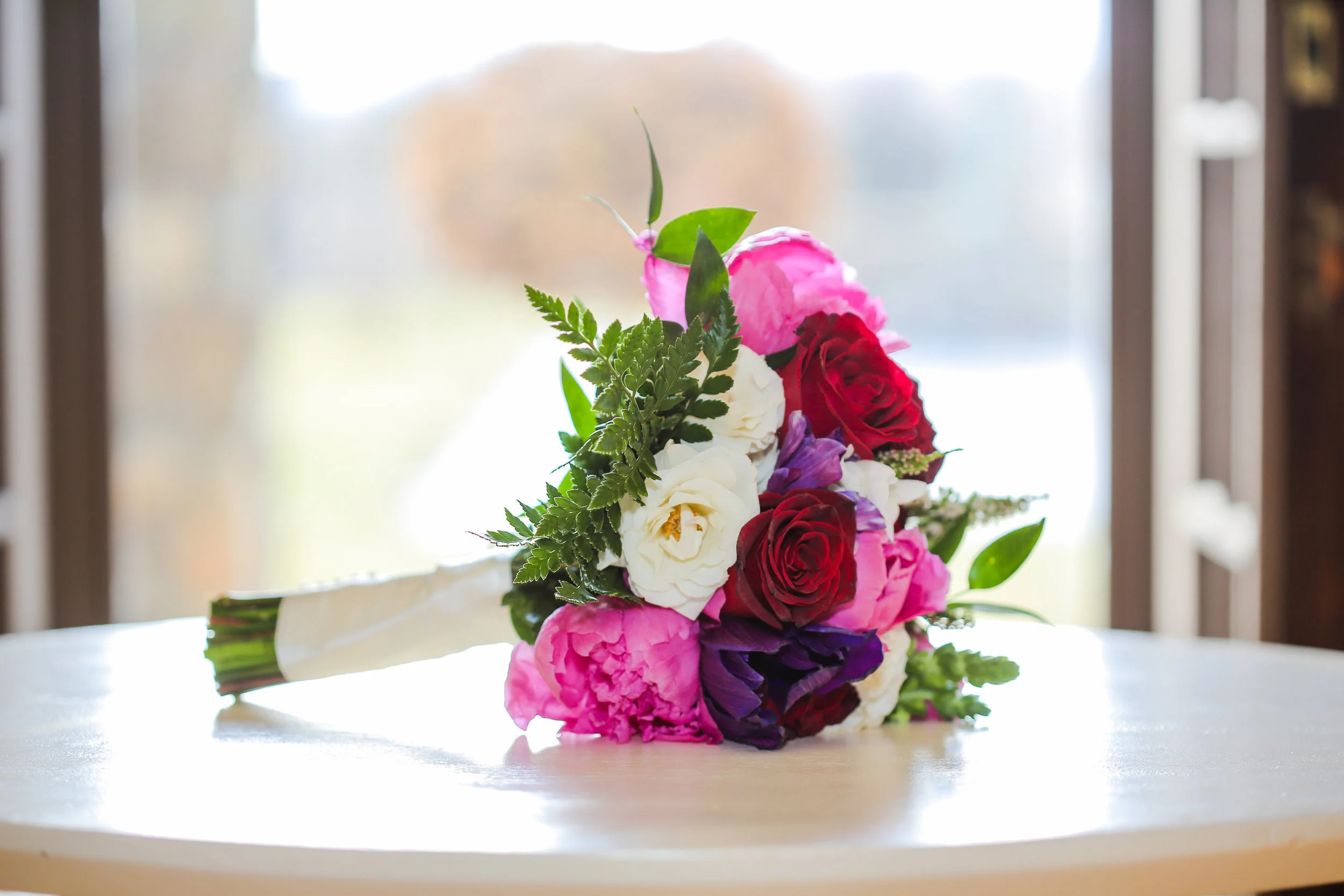 Bridal bouquet with deep purple anemone, pink peonies and red roses. This is perfect for a bride that loves bright colors. Raiza Vega Photography