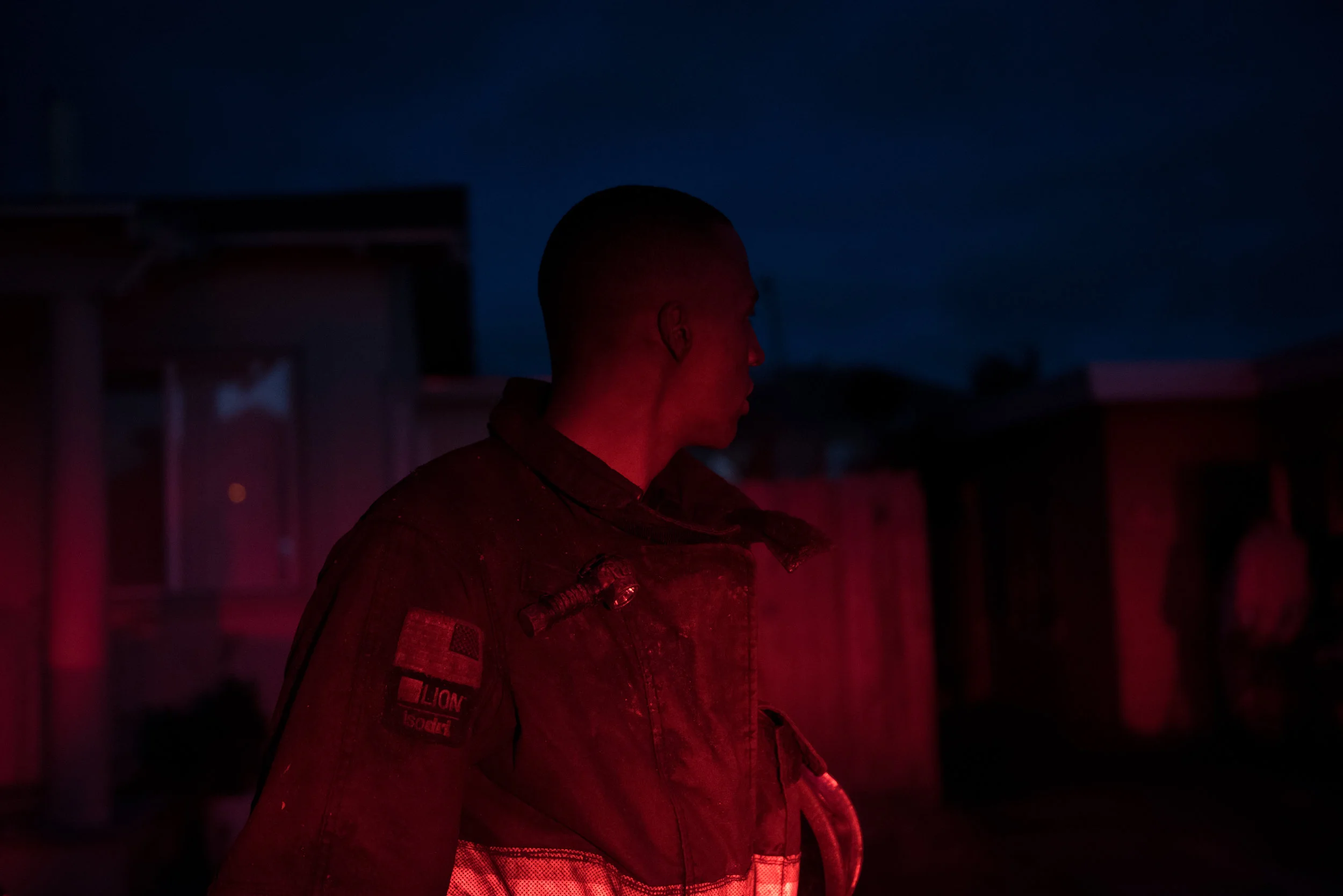 Firefighter Paul Mason Jr looks back at a burned house after fighting his first fire on Monday, June 26, 2017. | Rosa Furneaux for the East Bay Express