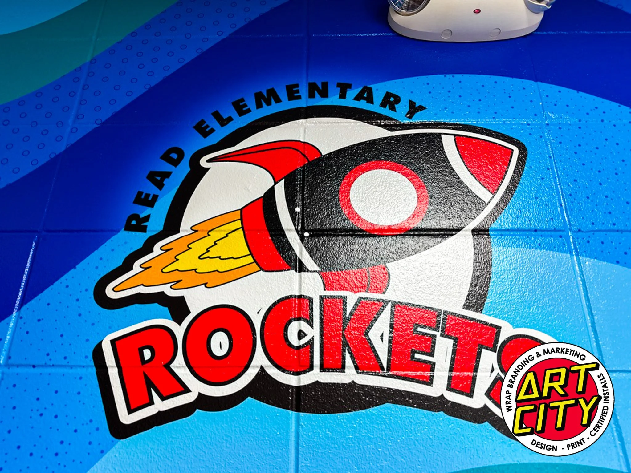 Colorful school floor mat with a rocket graphic and the words "Ready Elementaray Rocket" and a circular logo reading "Art City Wrap Branding & Marketing Design Print Certified Install".