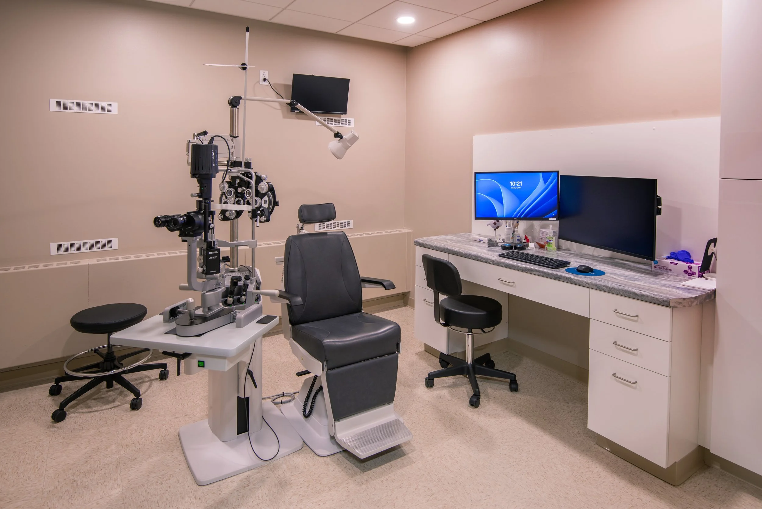 patient exam room for optometrist with chair, optical devices, desk and computer screen