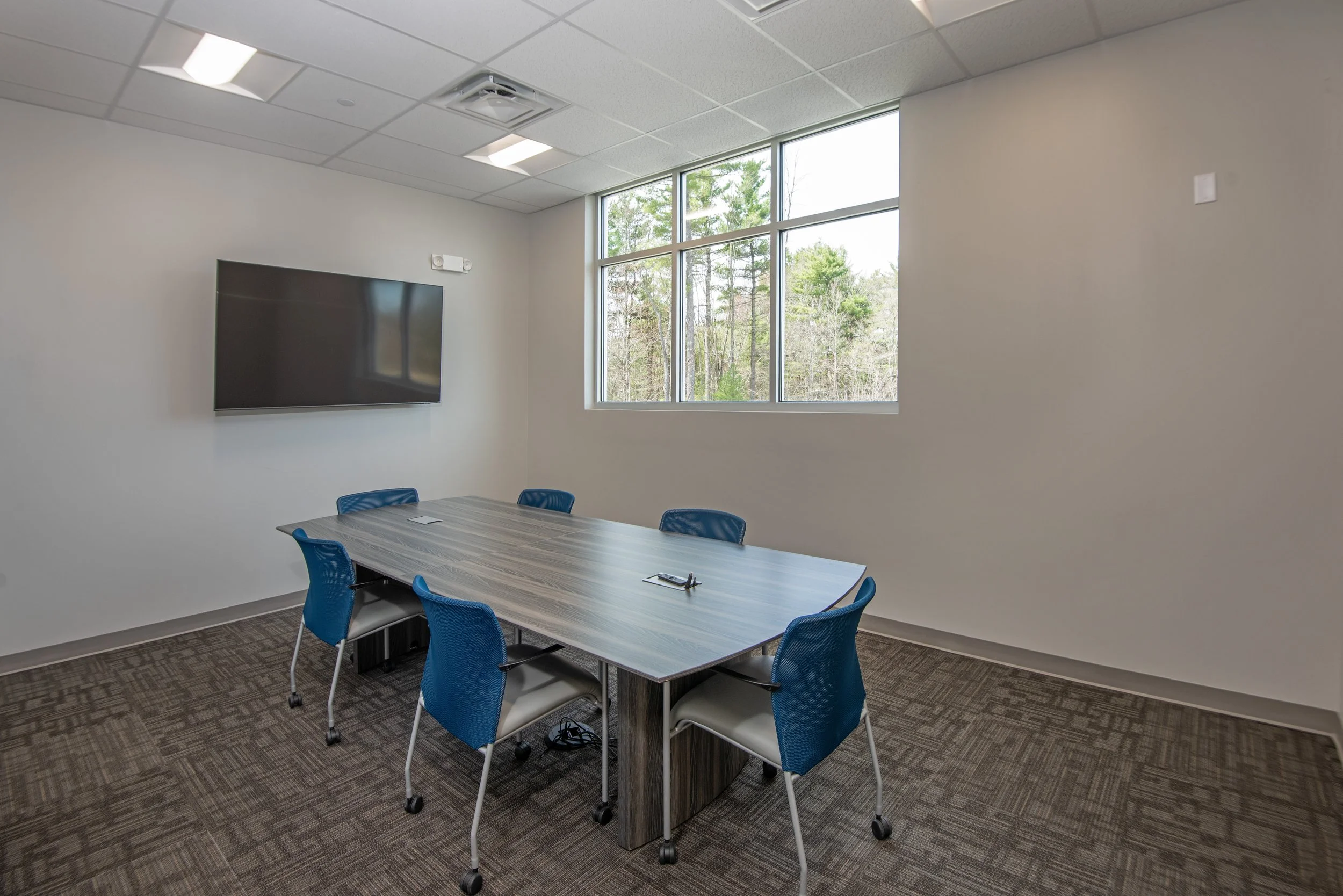 meeting room with table, chairs, and wall mounted screen