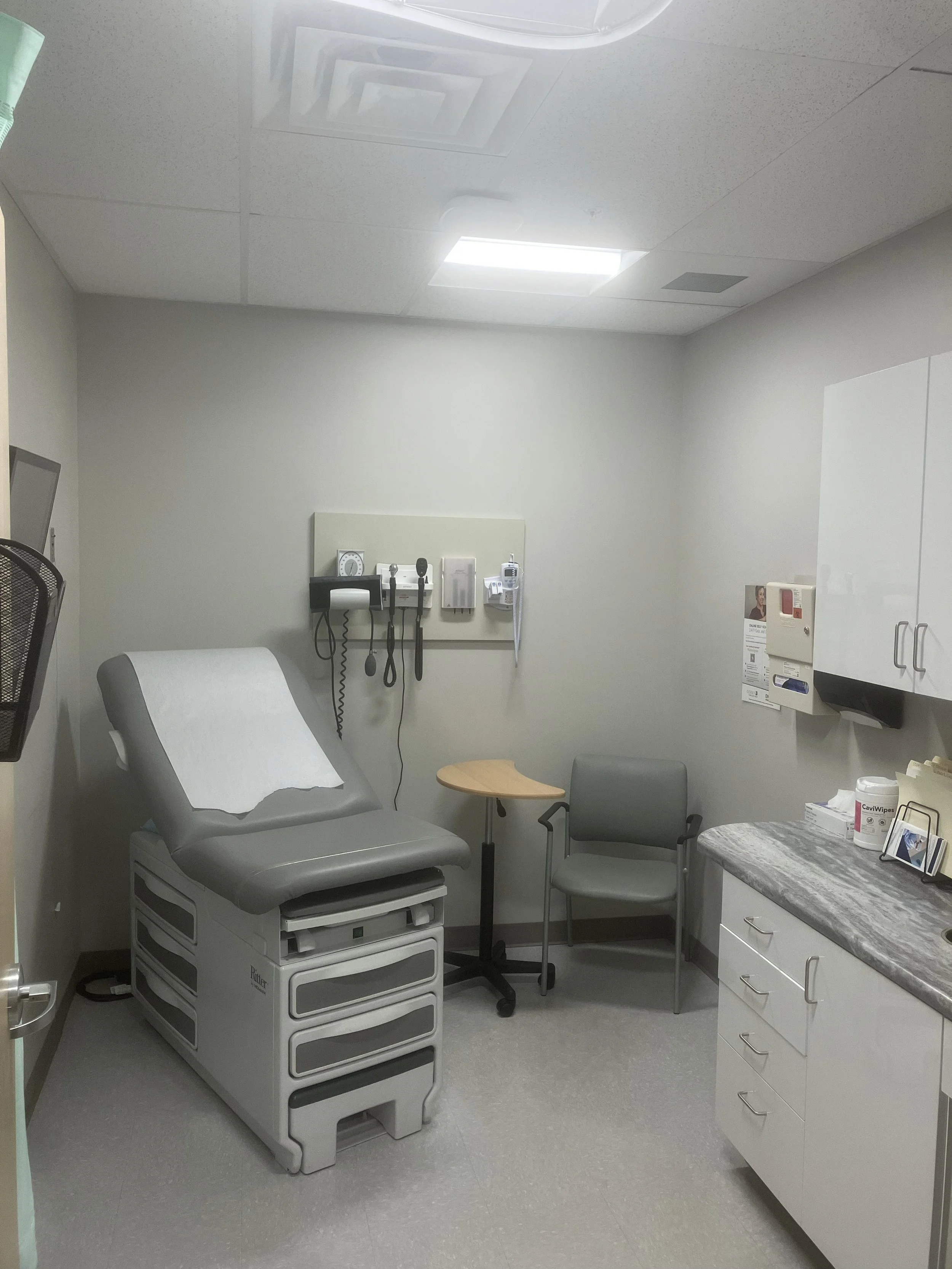 medical center exam room with exam table, chair, and cabinets