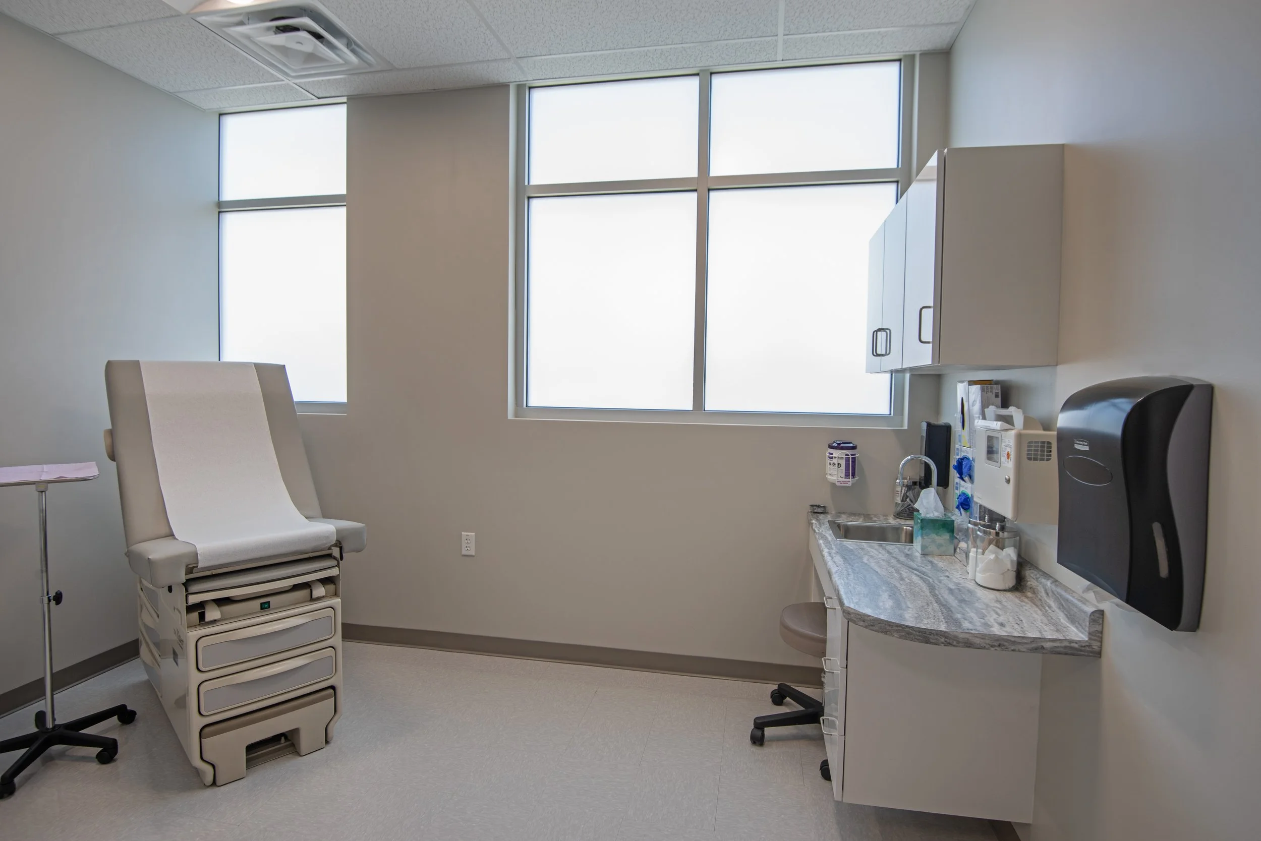 patient exam room with exam table, cabinets and large windows
