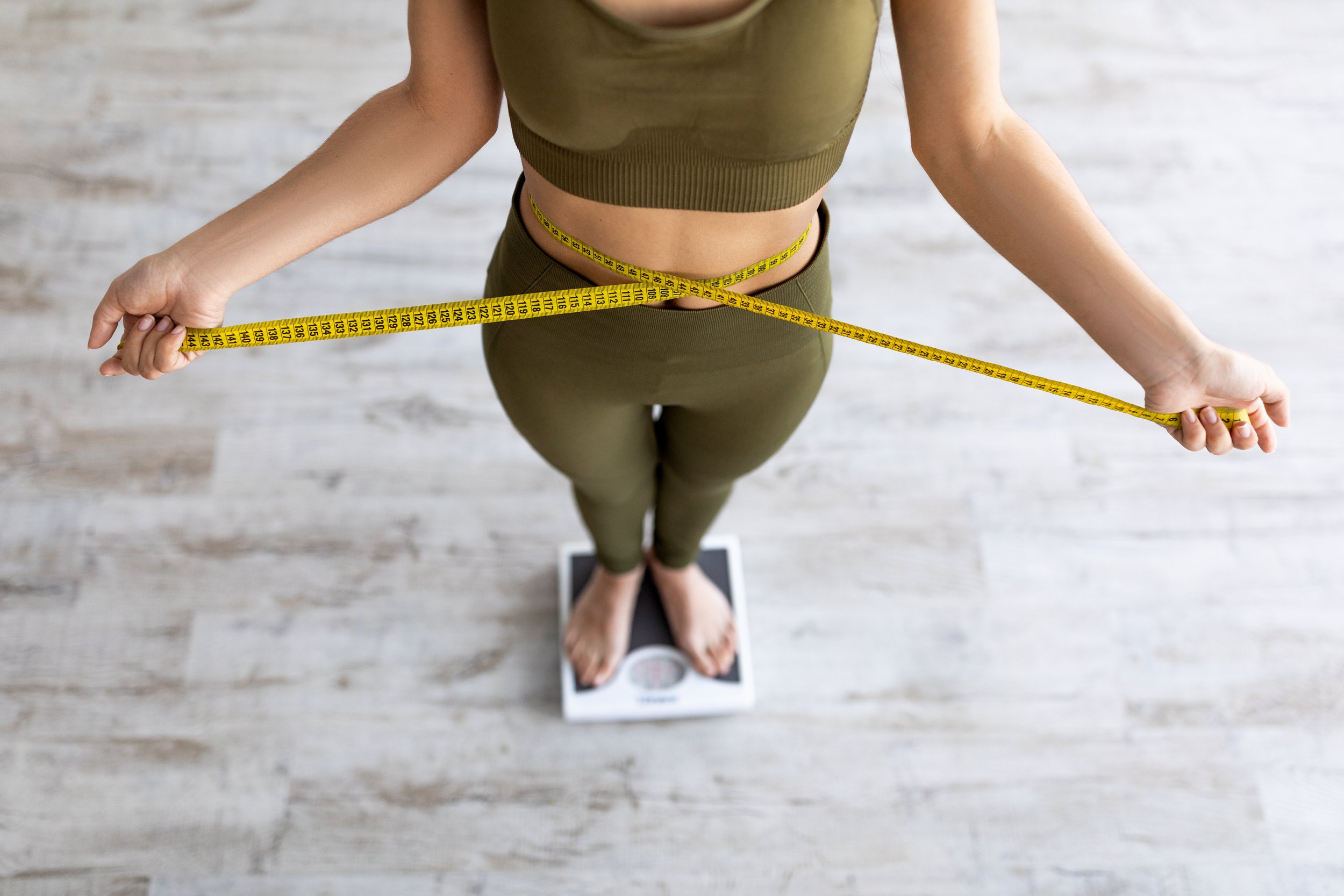 Fit and healthy young lady measuring her waist with a tape measure