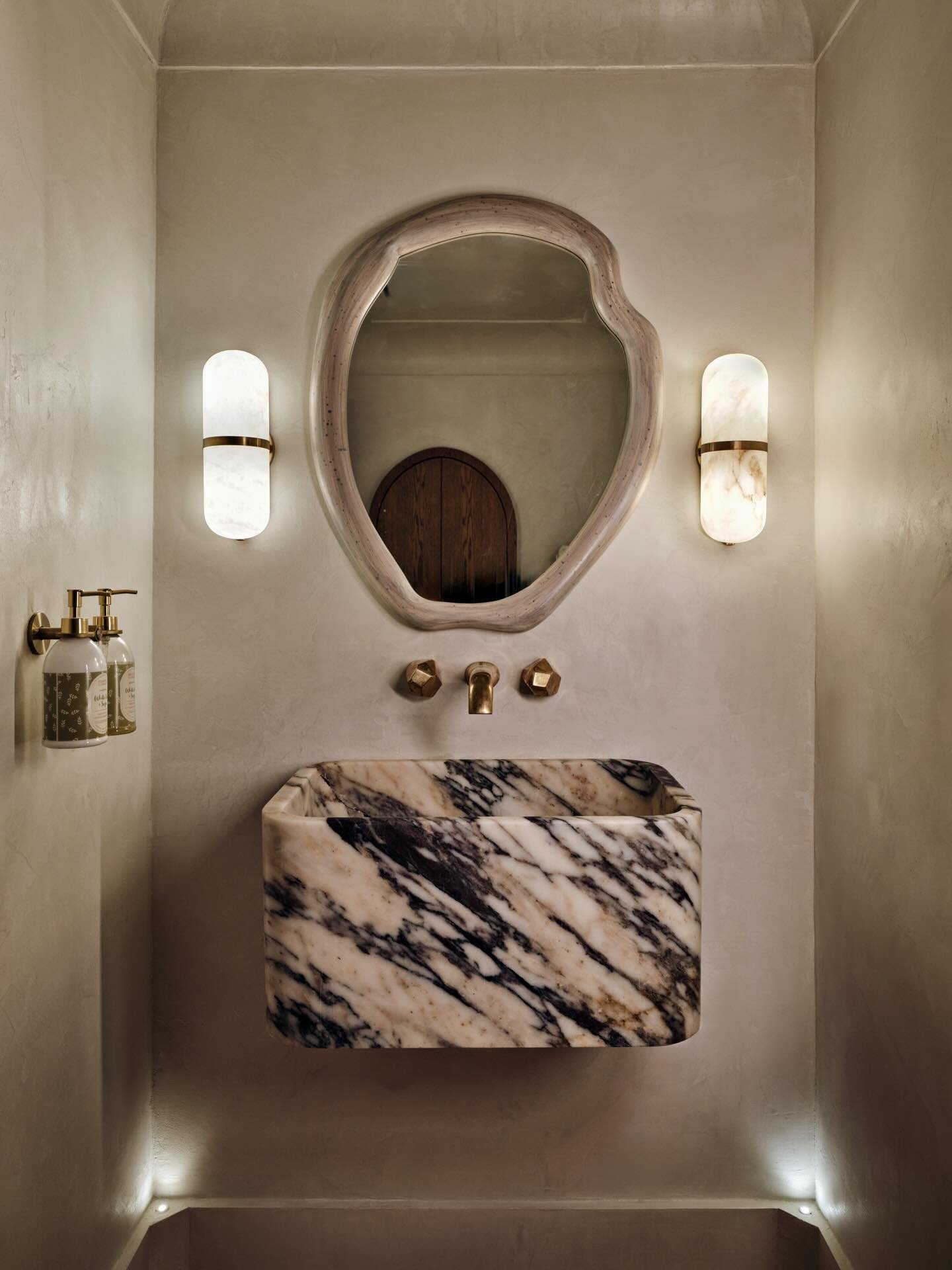 A powder room conceived as a sanctuary. A monolithic marble vessel appears to float, defined by subtle uplighting and a sculpted cove that amplifies a sense of weightlessness. The composition is restrained yet atmospheric, where material, light, and 