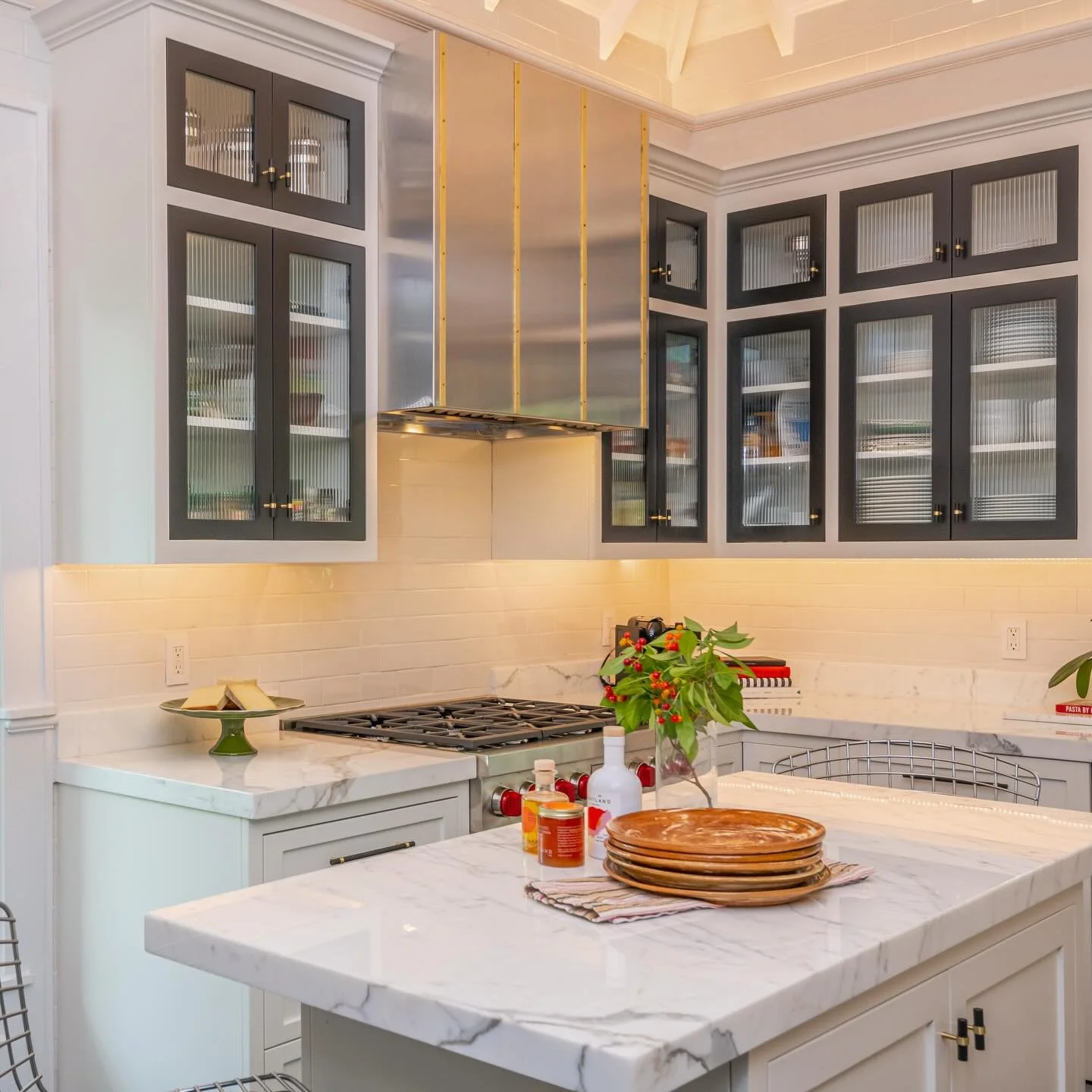 A study in black and white&mdash;refined, but with a pulse. Inset cabinetry with textured glass softens the symmetry, while a steel and brass hood introduces a tailored contrast that feels both industrial and elevated. Precision, with personality.

#