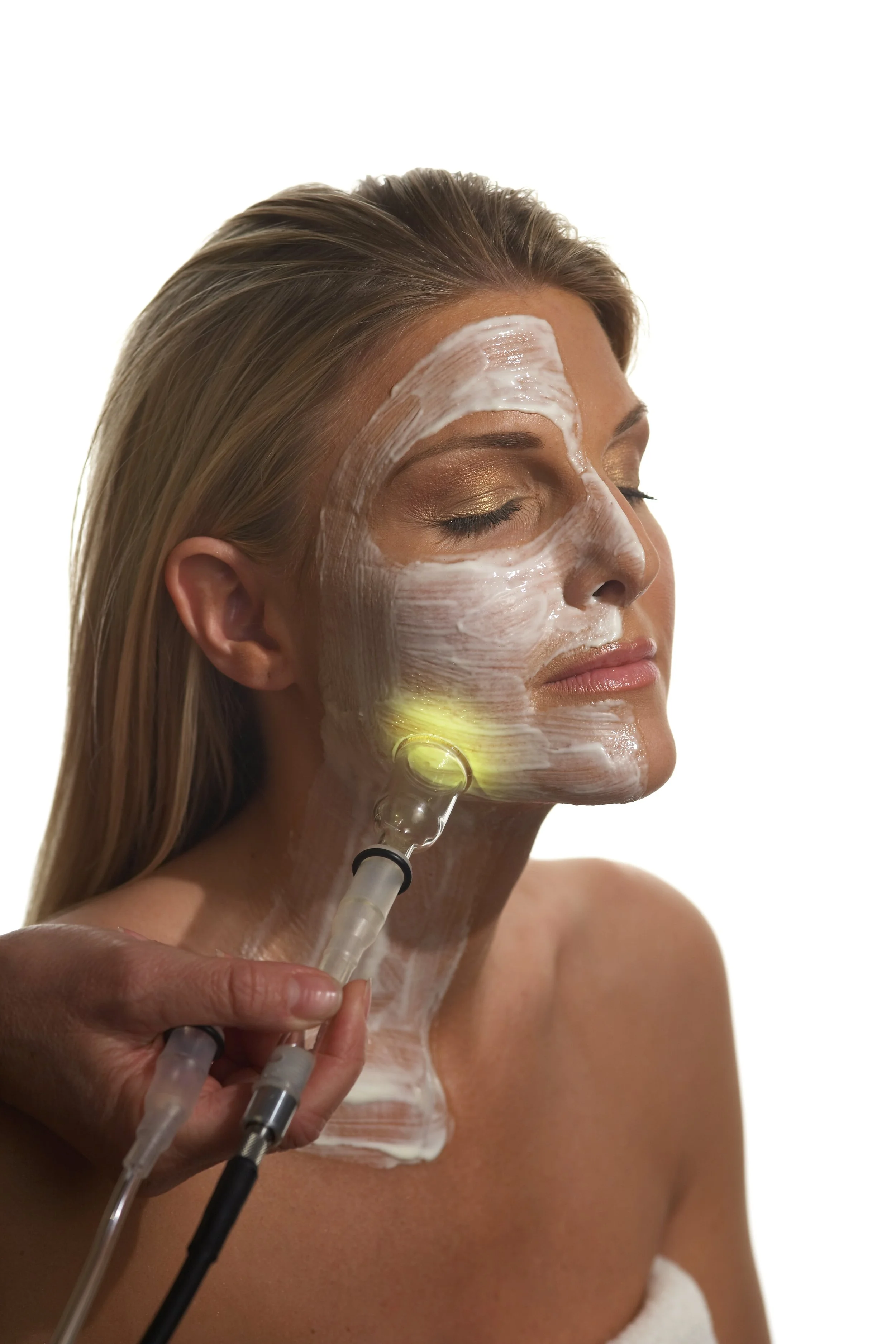 A woman receiving a PHYTO5 facial with quantum energetic skincare products and a lymphatic drainage enhanced with colored light therapy