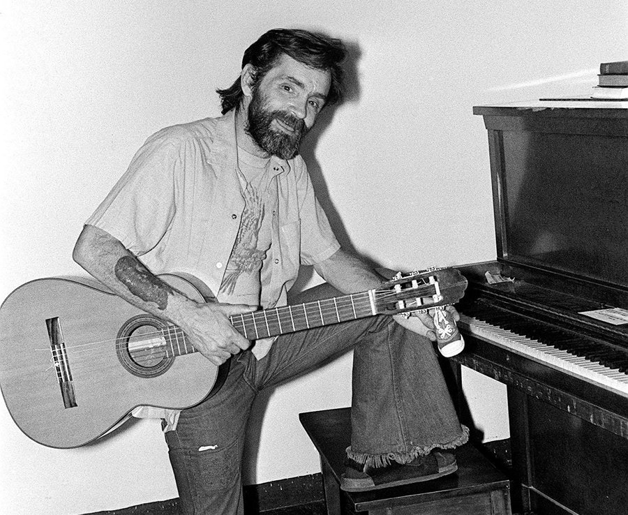 Charles Manson holding his guitar. 