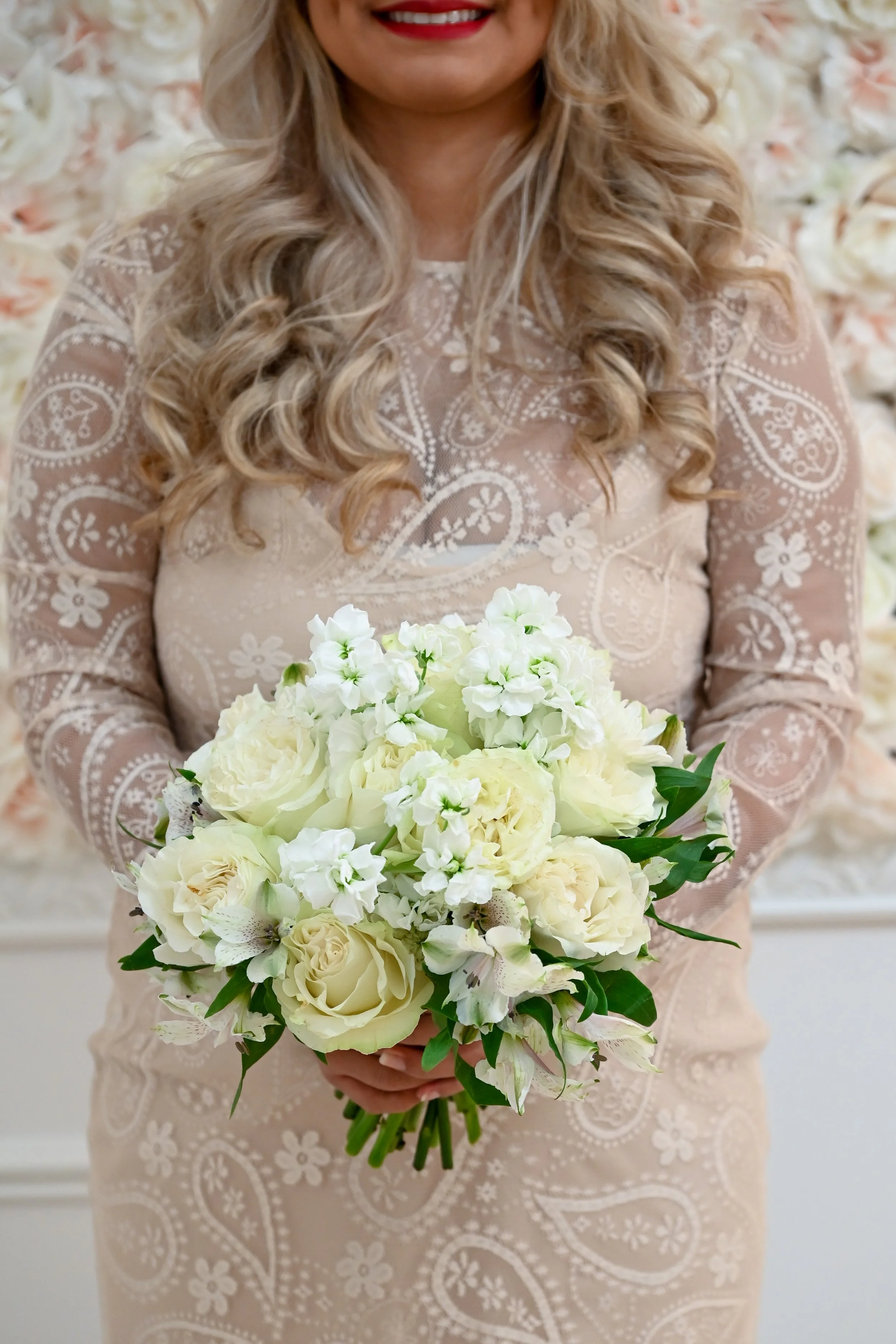 A woman in a lace dress holding a bouquet of white flowers.