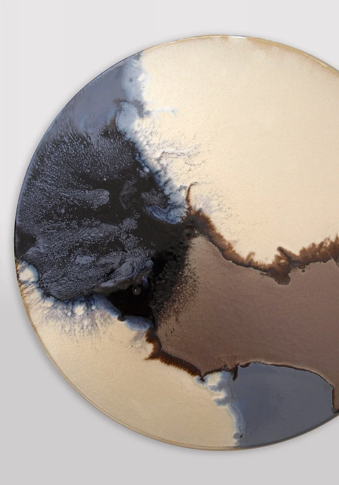 Abstract circular artwork with black, white, gray, and beige ink or paint splashes creating a swirling pattern.