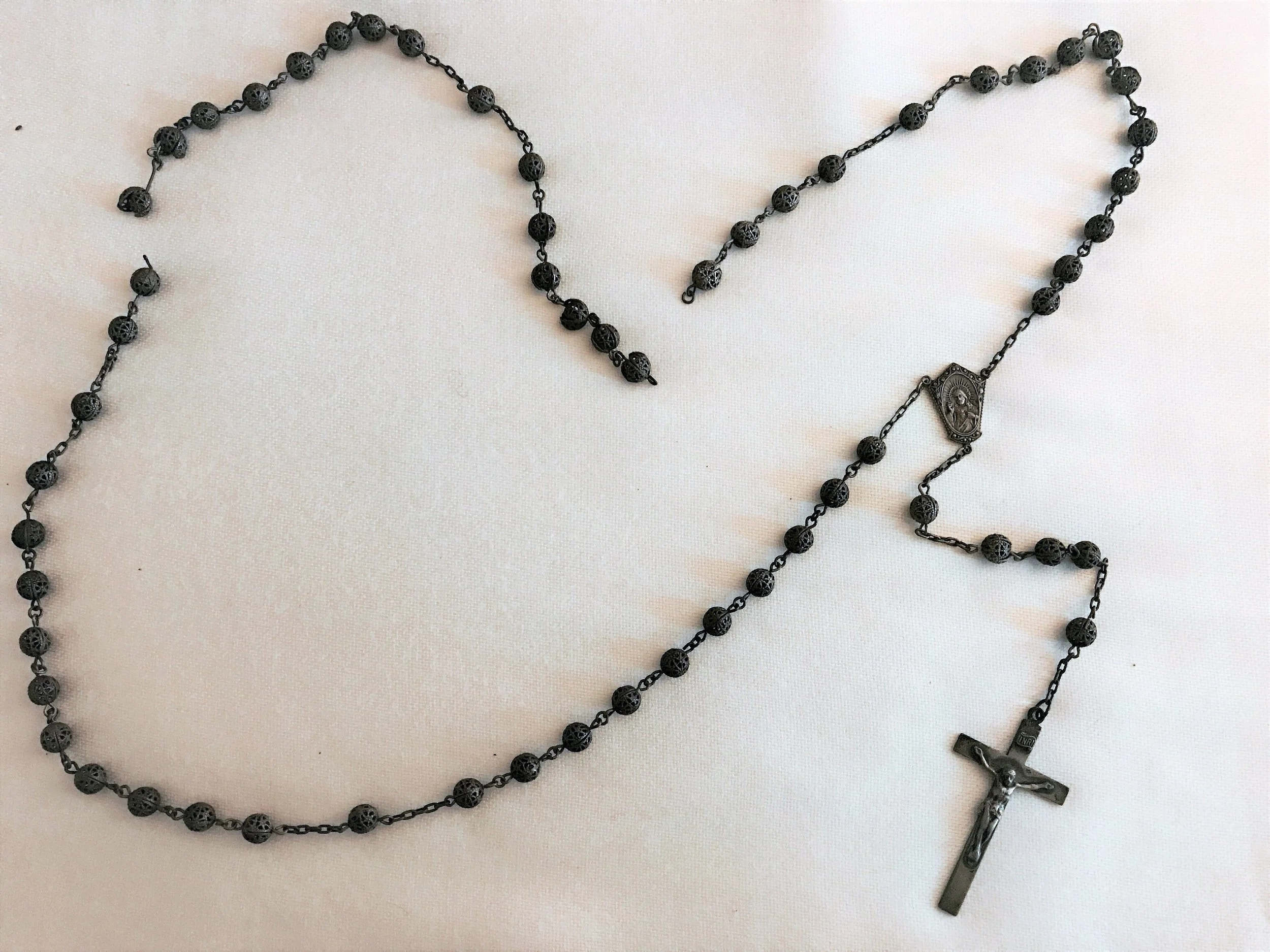 This vintage rosary was made of sterling silver filigree beads with sterling silver crucifix and centerpiece. Two of the beads were badly damaged and the rosary itself was so tarnished that it appeared black.