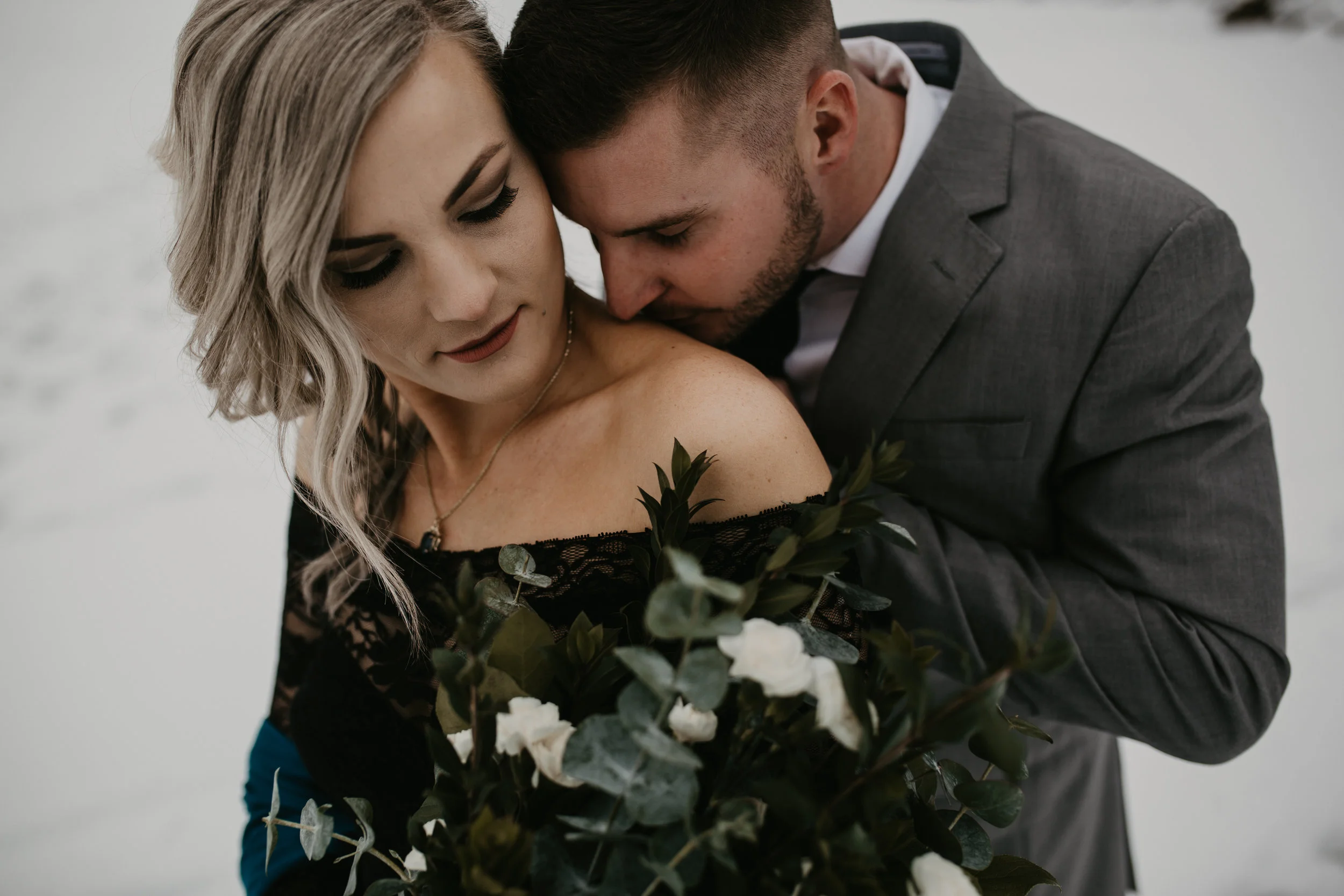 Groom kissing his bride standing on a frozen lake in Coeur d Alene Idaho