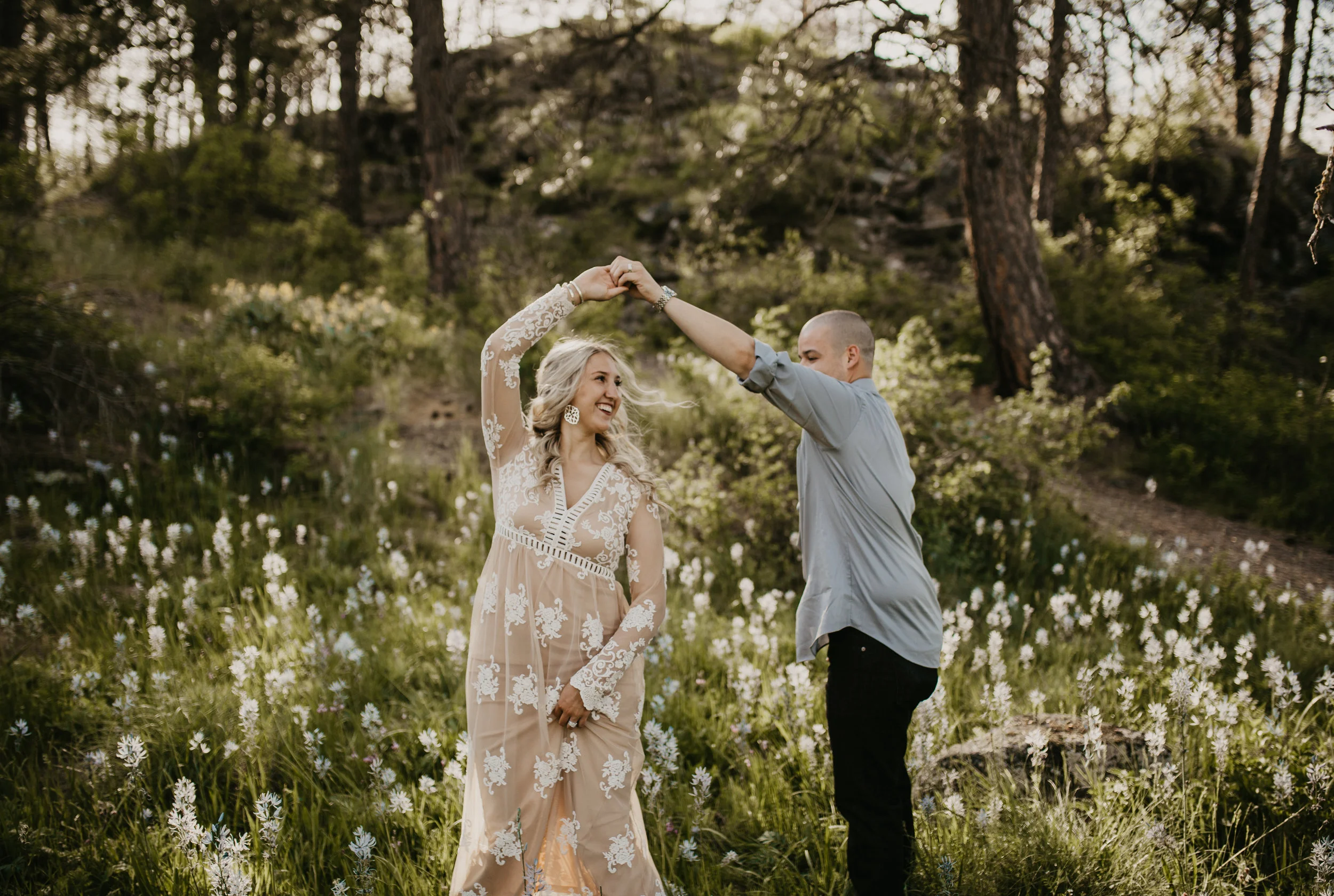 Couple dancing during engagement session in a field of wildflowers