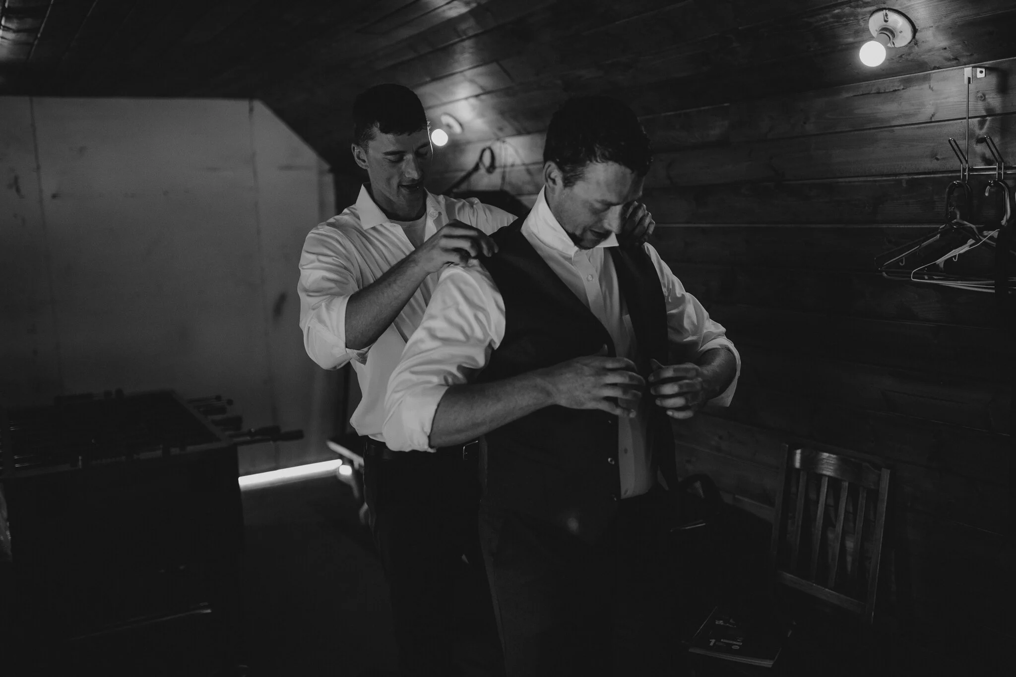 Groomsman helping the groom get ready for his first look