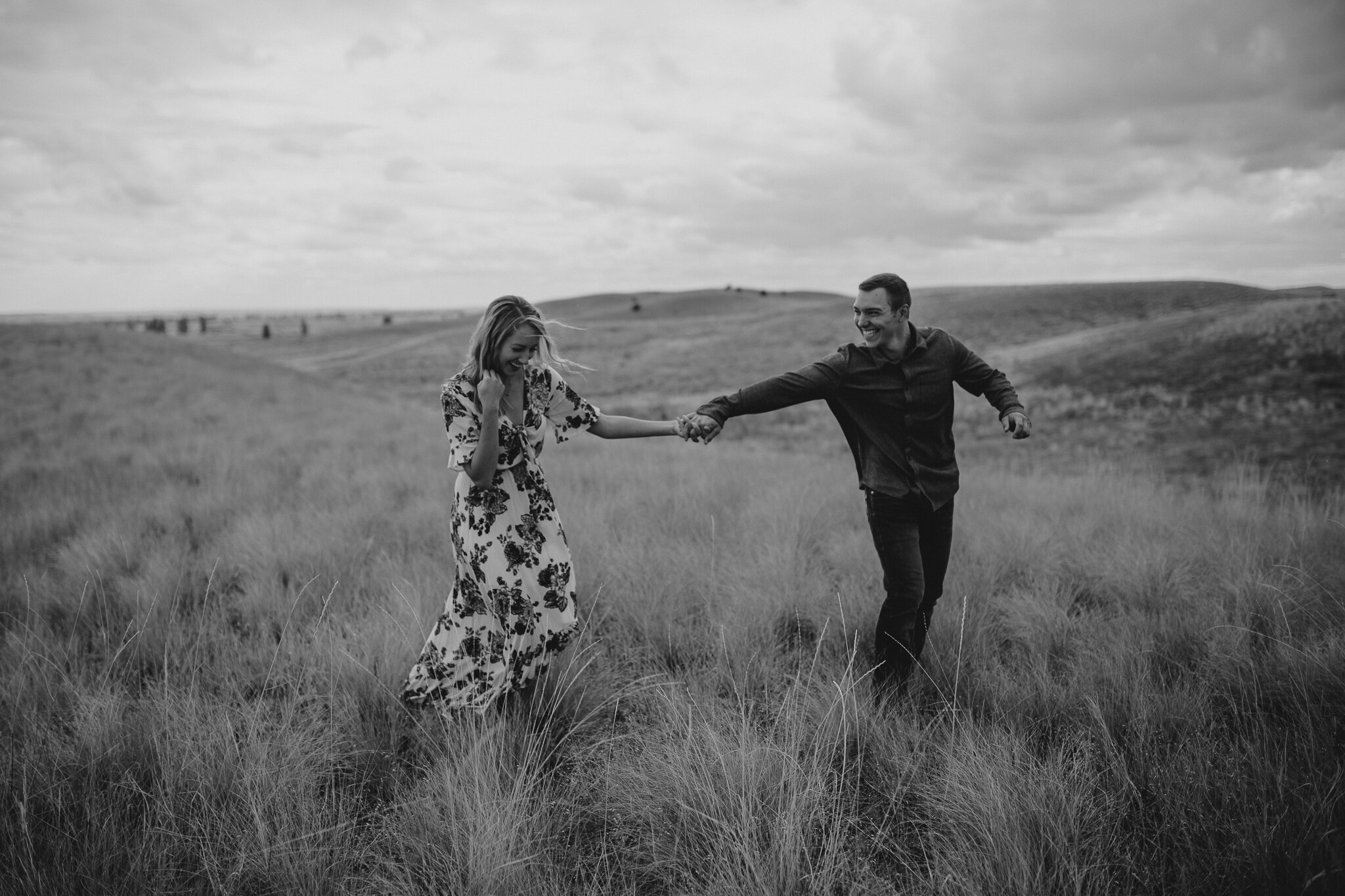  black and white image of couple holding hands in field 