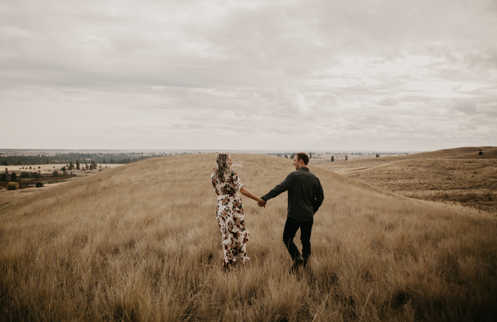  Couple running through a field during engagement session 