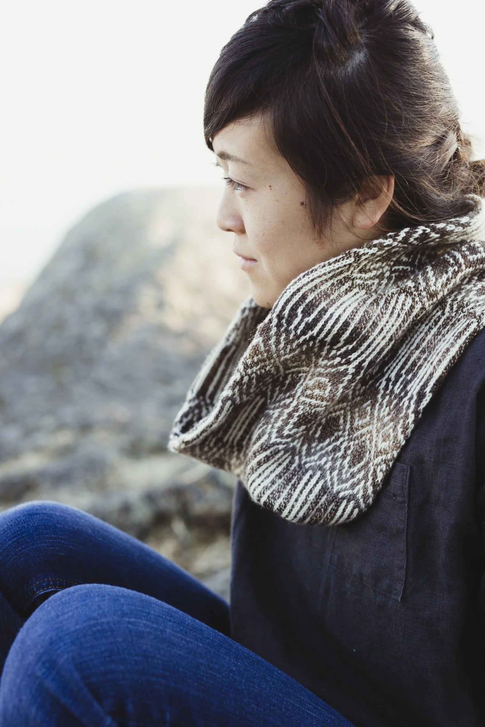 Ayako is wearing a brown, beige, and white cowl with intricate colourwork.
