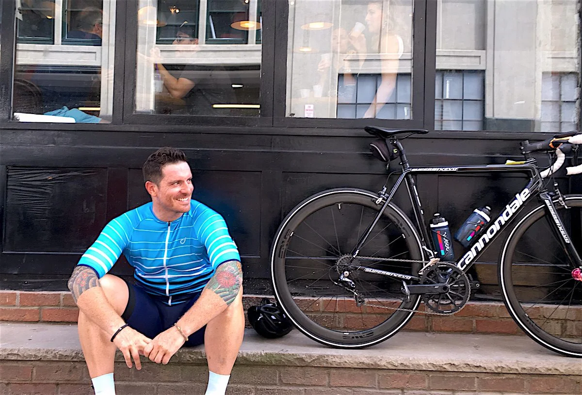 Seamus Mullen sits on a curb next to his bike