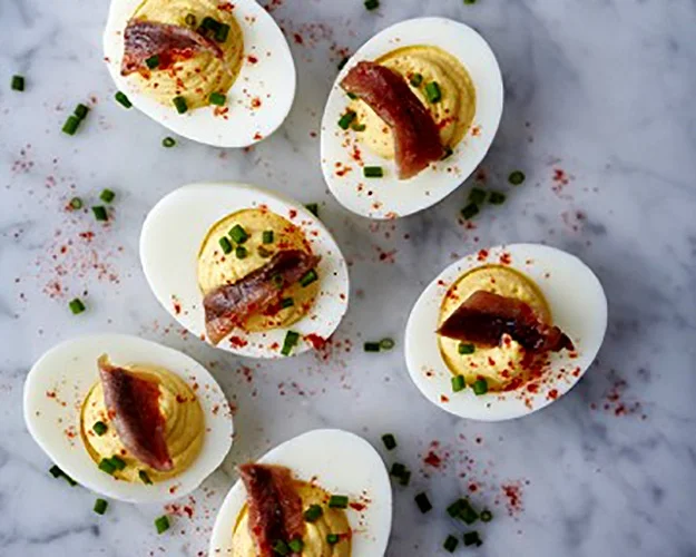 Deviled Eggs with Anchovies and Rosemary served on a marble slab