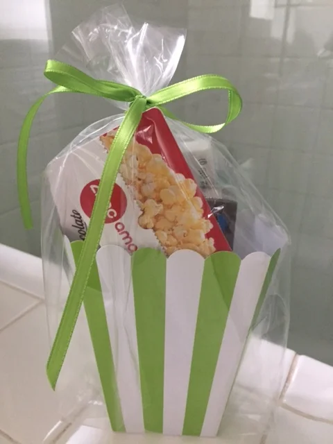 A Movie Basket is a great gift. Movies are a fun summer activity( ac!) and you can play around with different candies, gourmet popcorn and gift cards. Make it an at home movie basket with a cute throw, Netflix gift card and microwave popcorn.