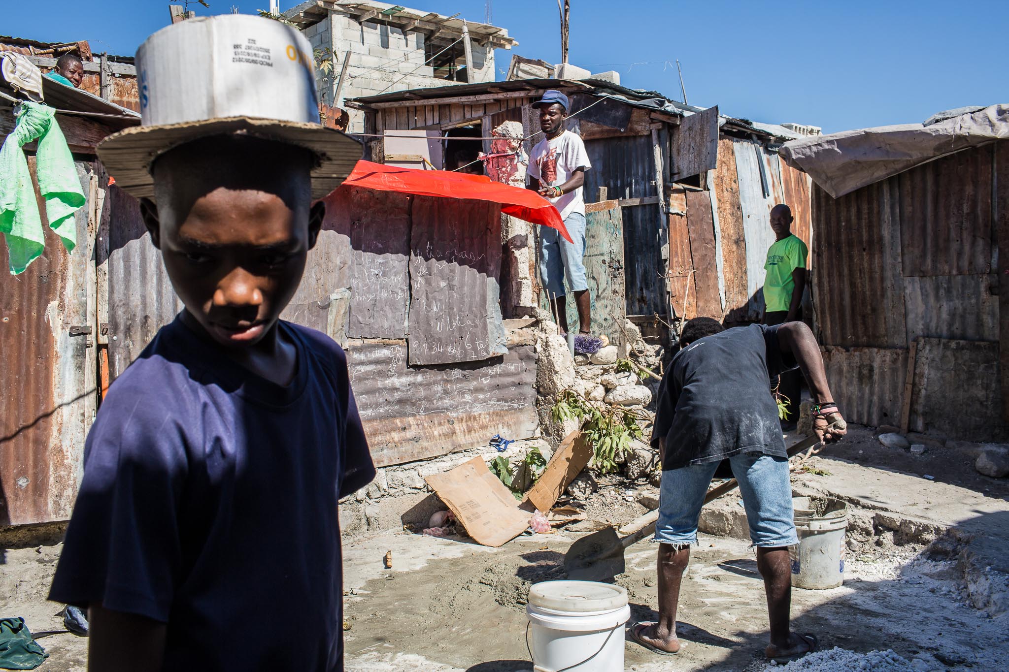  A boy wears a top hat he made himself out of cardboard as local residents work on repairing their houses on Thursday, December 18, 2014 in Port-au-Prince, Haiti. Fort National was among the hardest hit areas of Port-au-Prince in the 2010 earthquake,