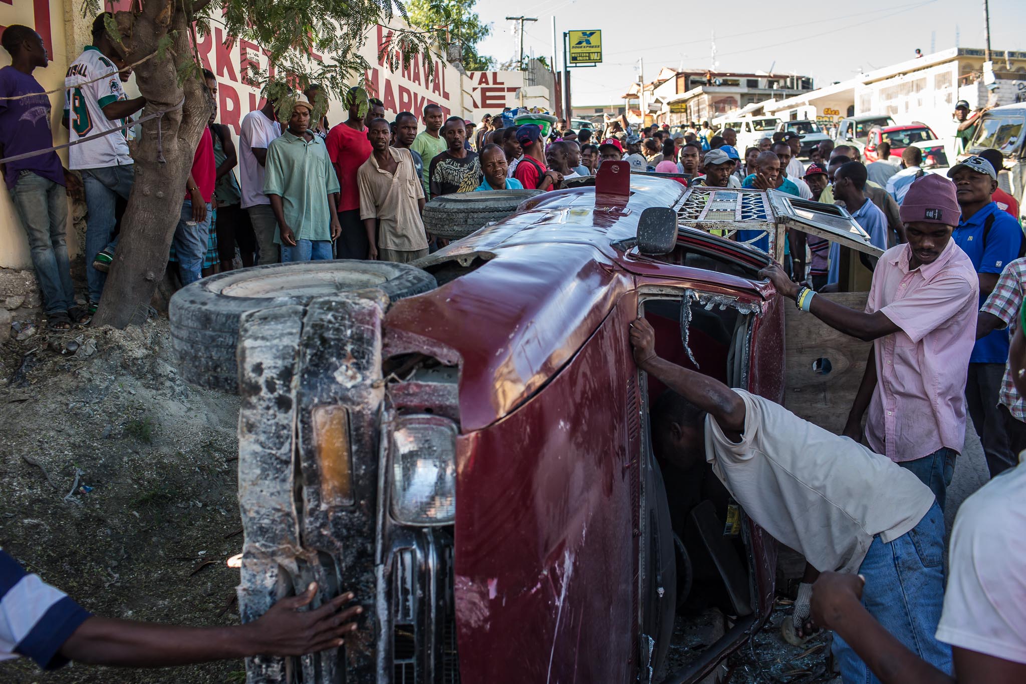  A tap-tap which flipped over during a morning rush-hour accident is inspected by a curious crowd on Thursday, December 18, 2014 in Port-au-Prince, Haiti. No one was injured in the accident. 