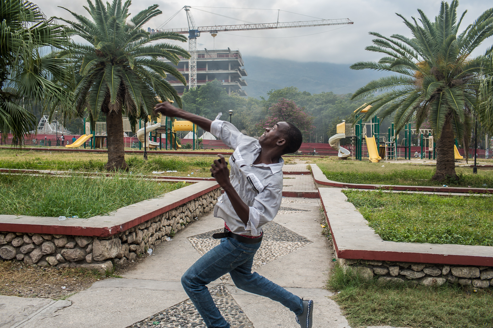  An anti-government protester throws a rock at pro-government supporters on Tuesday, December 16, 2014 in Port-au-Prince, Haiti. President Michel Martelly was elected in 2010 with great hope for reforms, but in the wake of slow recovery and parliamen