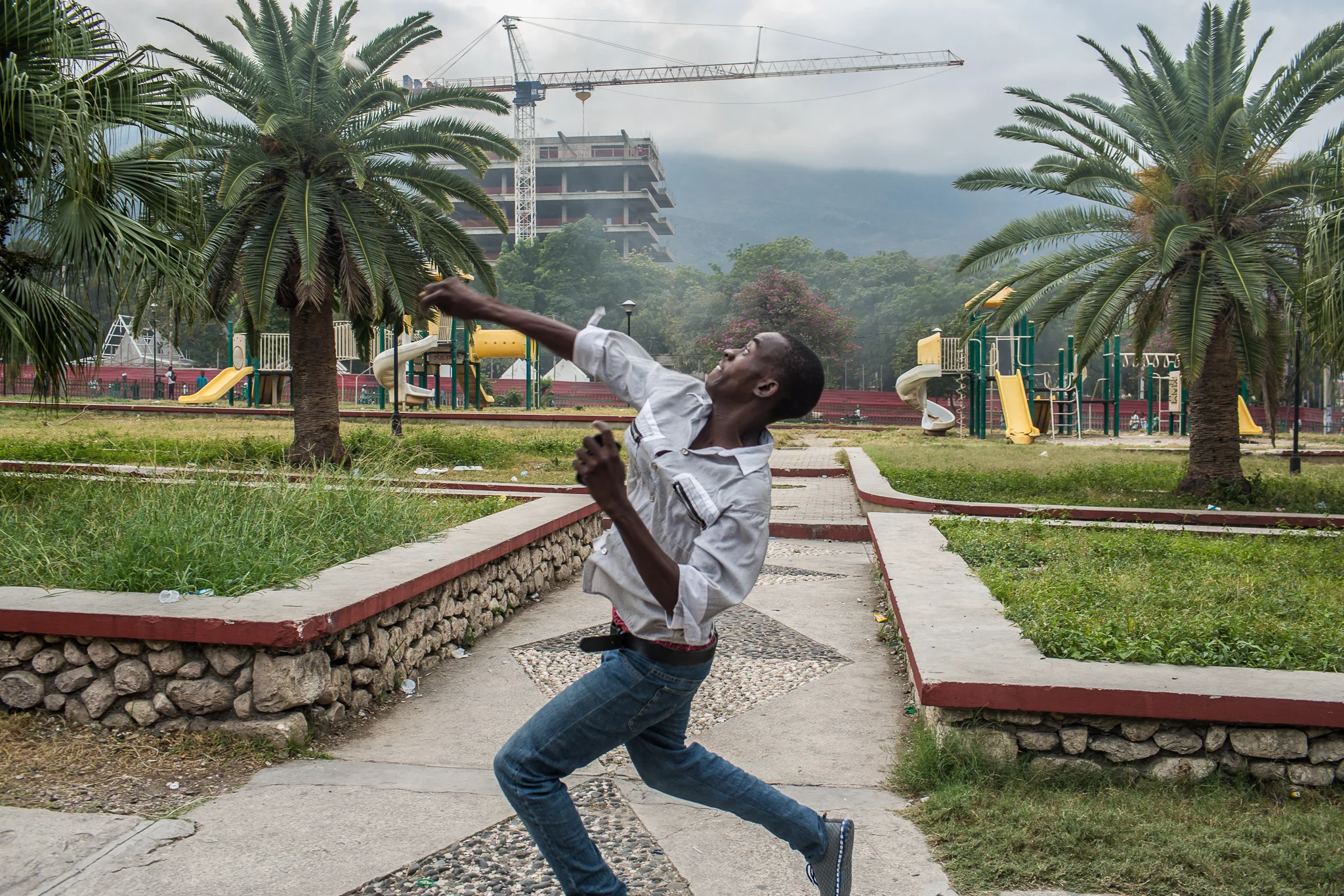 An anti-government protester throws a rock at pro-government supporters on Tuesday, December 16, 2014 in Port-au-Prince, Haiti. President Michel Martelly was elected in 2010 with great hope for reforms, but in the wake of slow recovery and parliamentary elections that are three years overdue, his popularity has suffered tremendously, forcing Prime Minister Laurent Lamothe to resign.