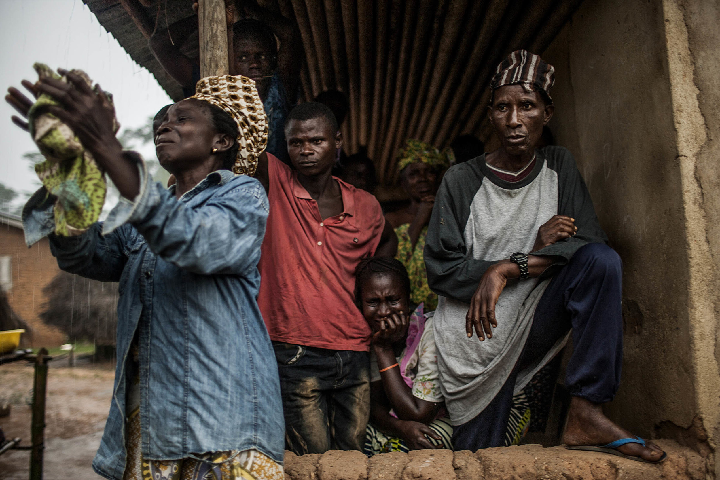  Relatives of a man suspected of dying of Ebola look on as Red Cross workers pack his body in the village of Sengema, Sierra Leone on Saturday, August 16, 2014. Family and community members are encouraged not to touch the bodies of those suspected of