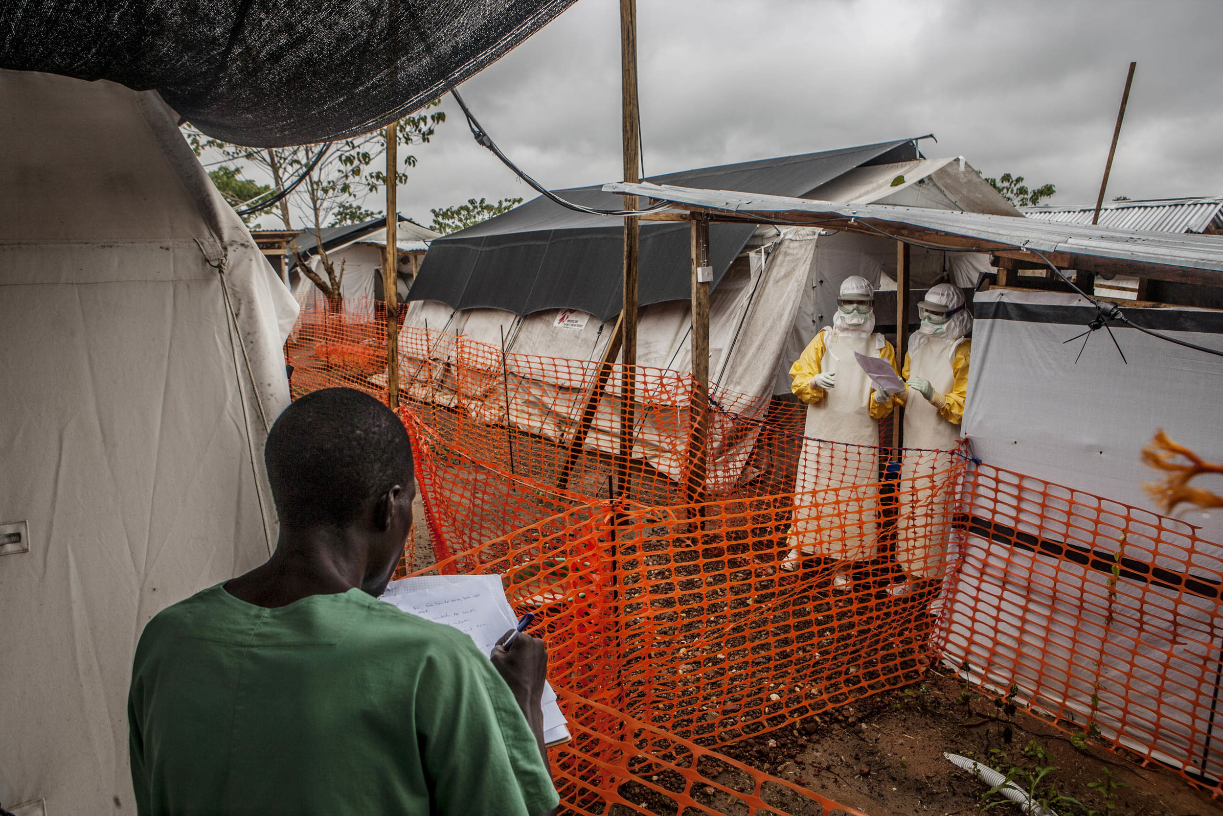  Doctors Without Borders medical staff discuss patient status across an established safety cordon in an Ebola treatment center in Kailahun, Sierra Leone on Sunday, August 17, 2014. Those in masks stand in the "high risk" zone where highly contagious 