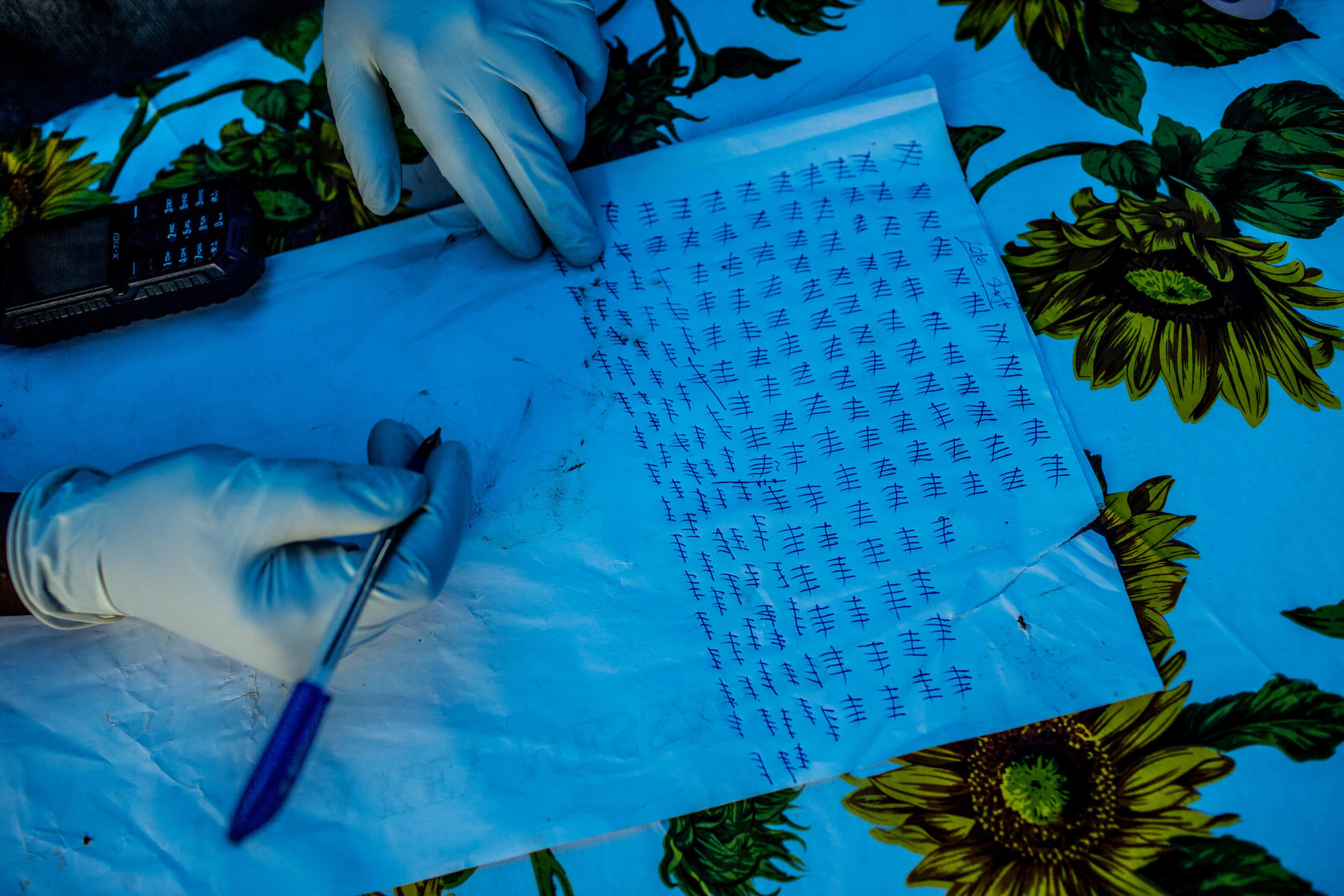  A government health worker keeps tally of those who pass an Ebola quarantine checkpoint in the road leading from Freetown to Kenema, Sierra Leone on Saturday August 16, 2014. The government of Sierra Leone has set up numerous checkpoints leading int