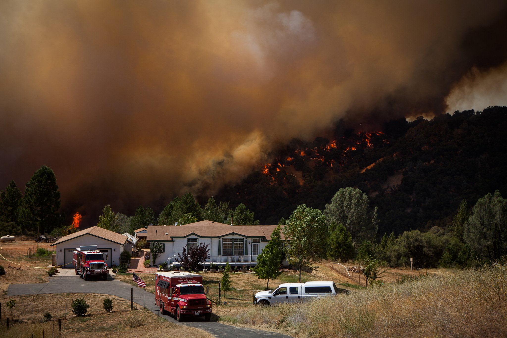  Firefighters protect an evacuated home while the Sand Fire burns behind it near Plymouth, California, July 26, 2014. 
The Sand Fire destroyed 20 homes and burned more than 4,200 acres near the town of Plymouth. 