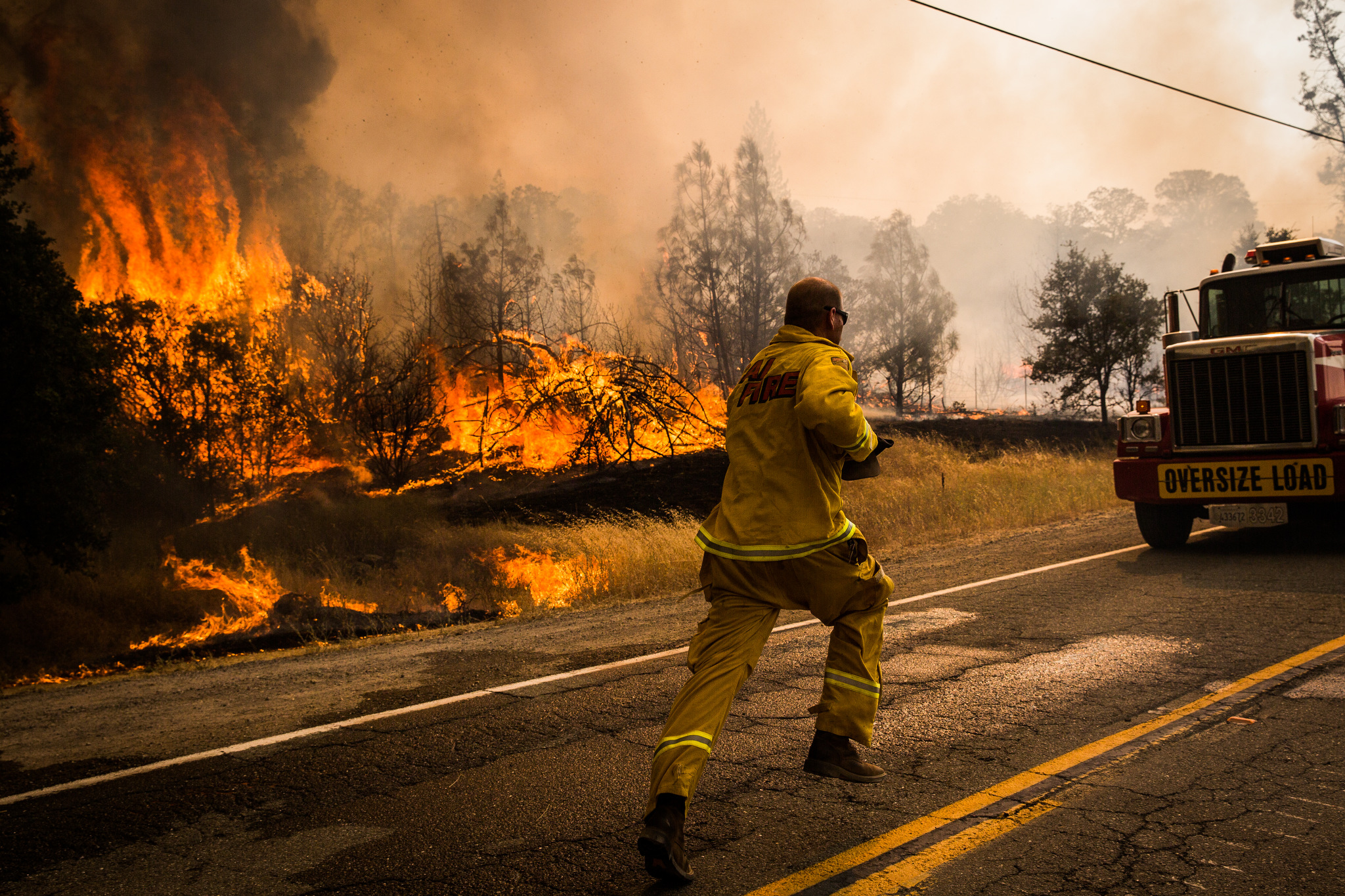  A firefighter runs to move a truck before it's overrun by a spot fire on the Rocky Fire in Lake County, California on July 30, 2015. As of August 5, the fire had consumed 69,600 acres and is one of 23 wildfires burning in California. 