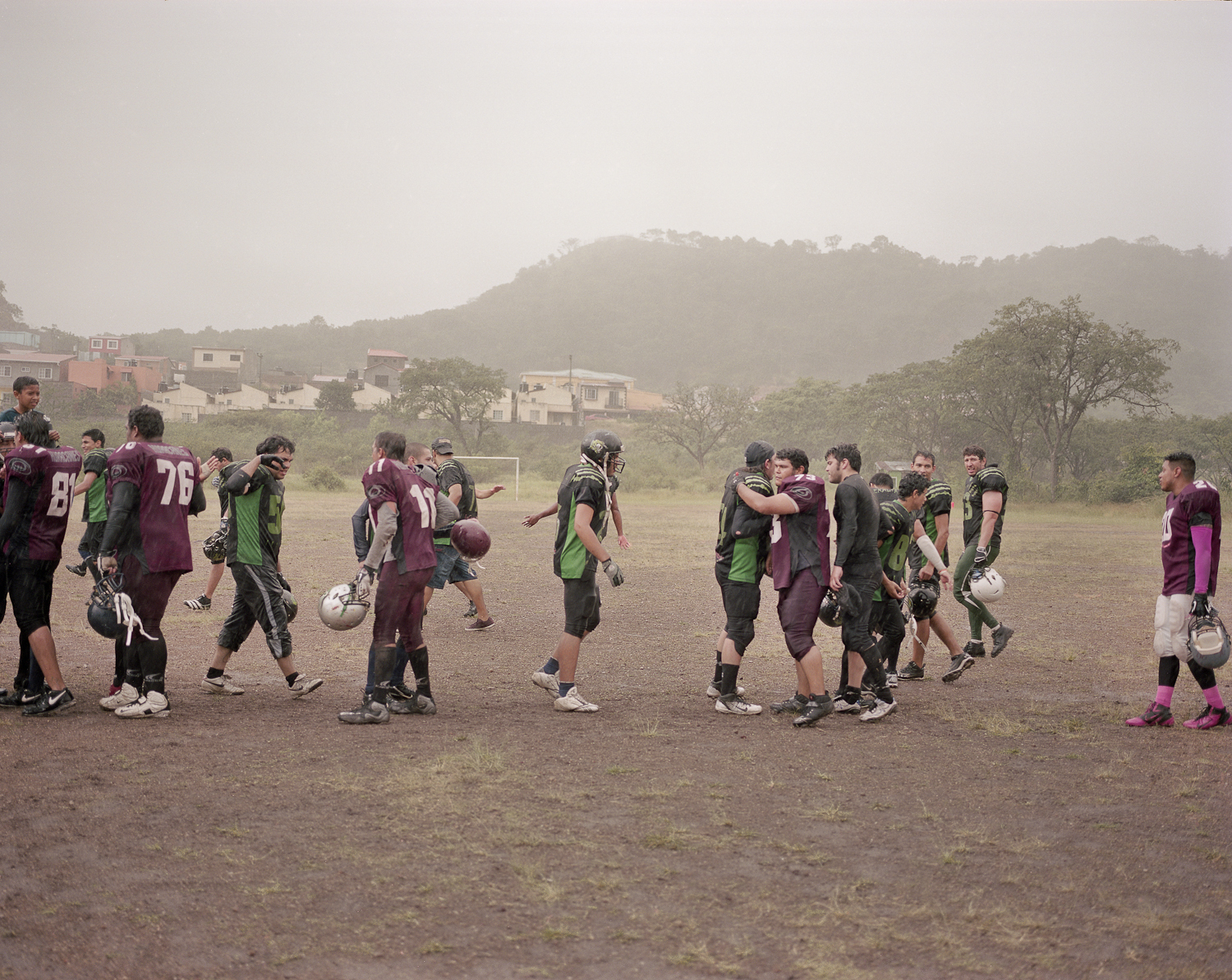  Two teams from the Honduran National American Football League congratulate each other in the rain after a game. 