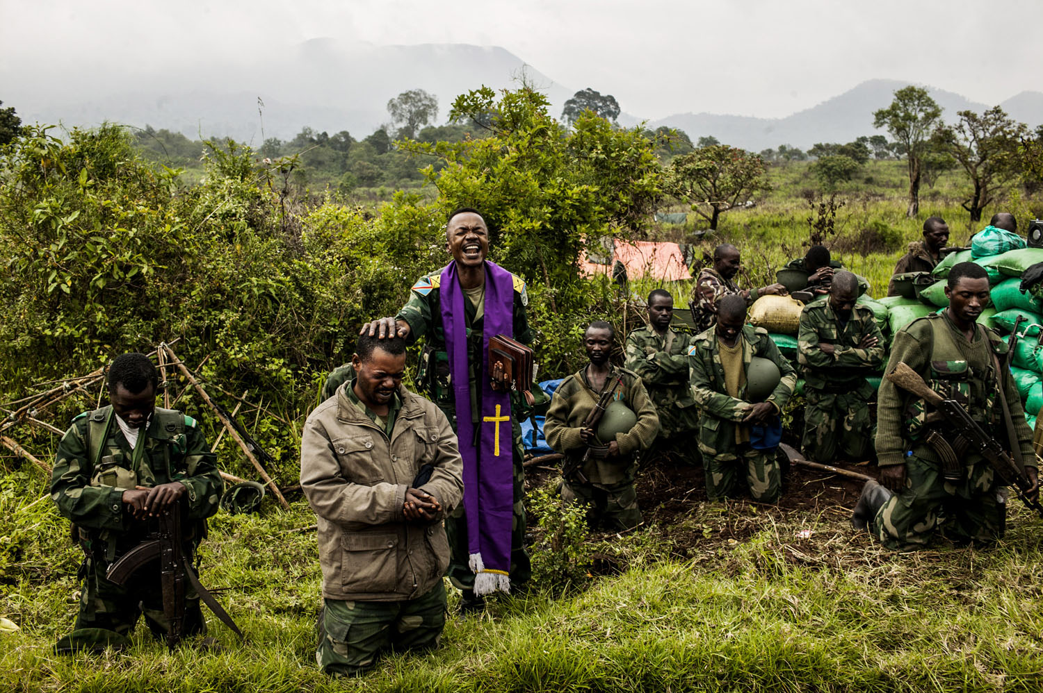  A Congolese military chaplain prays with soldiers at the frontline in Kibumba, outside Goma. This position is the furthest advance point of the military. Members of the M-23 rebel group are within shouting distance. 