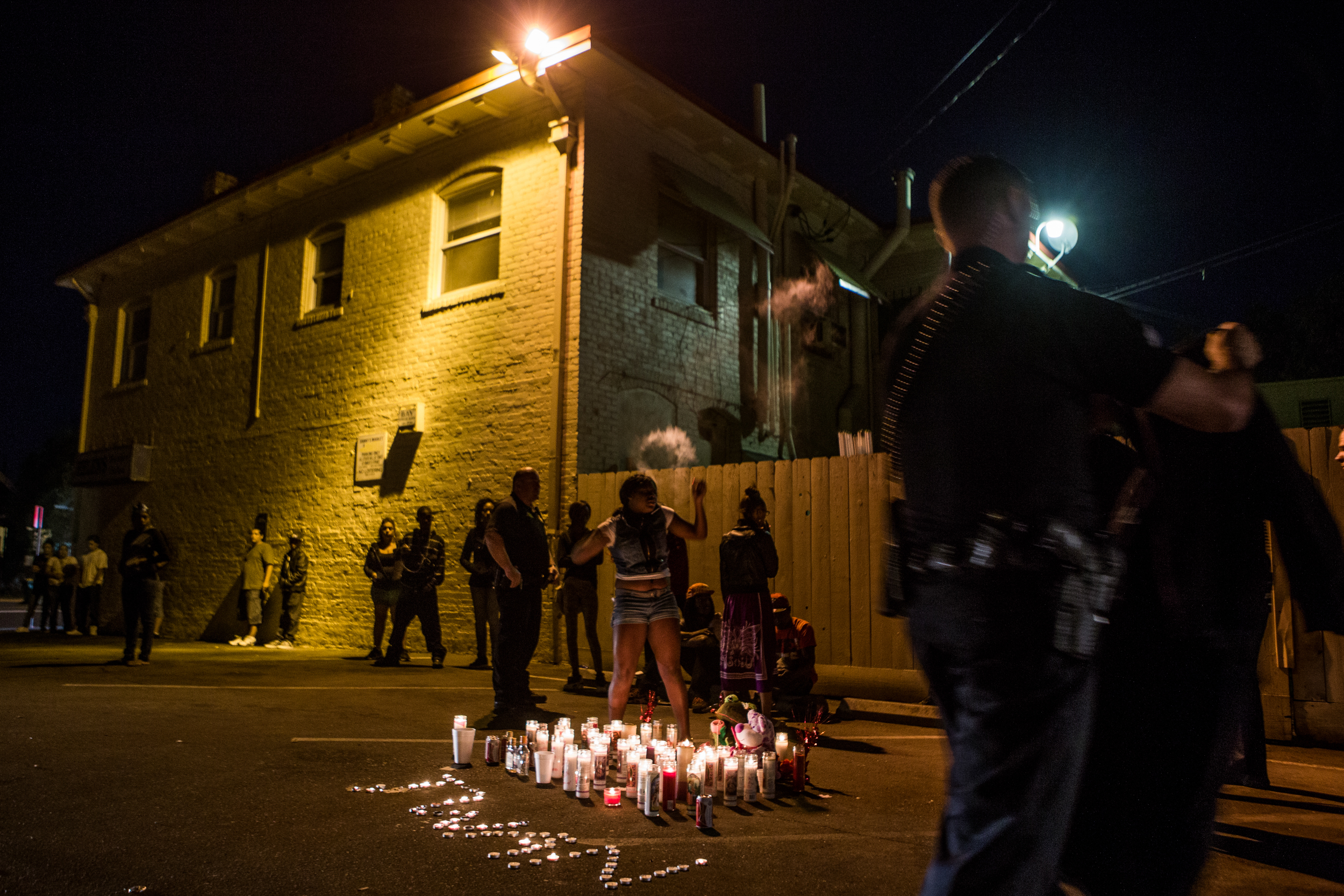  Members of Stockton's Community Response Team question mourners at the site of a memorial for five people shot the night before in Stockton, California, September 18, 2013. Facing stark and rising homicide rates, the California cities Oakland and St