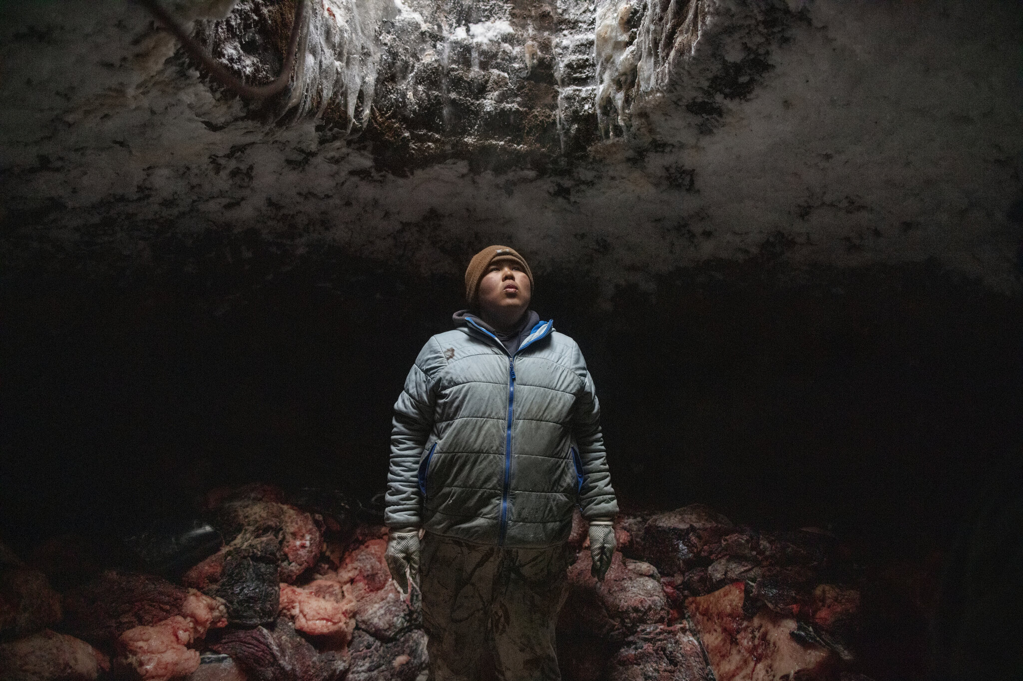  After a successful hunt, Josiah Olemaun, a young whaling crew member takes a break from moving and stacking whale meat into his family’s ice cellar in Utqiagvik, Alaska. April 29th, 2018. Ice cellars are generations-old massive underground freezers 