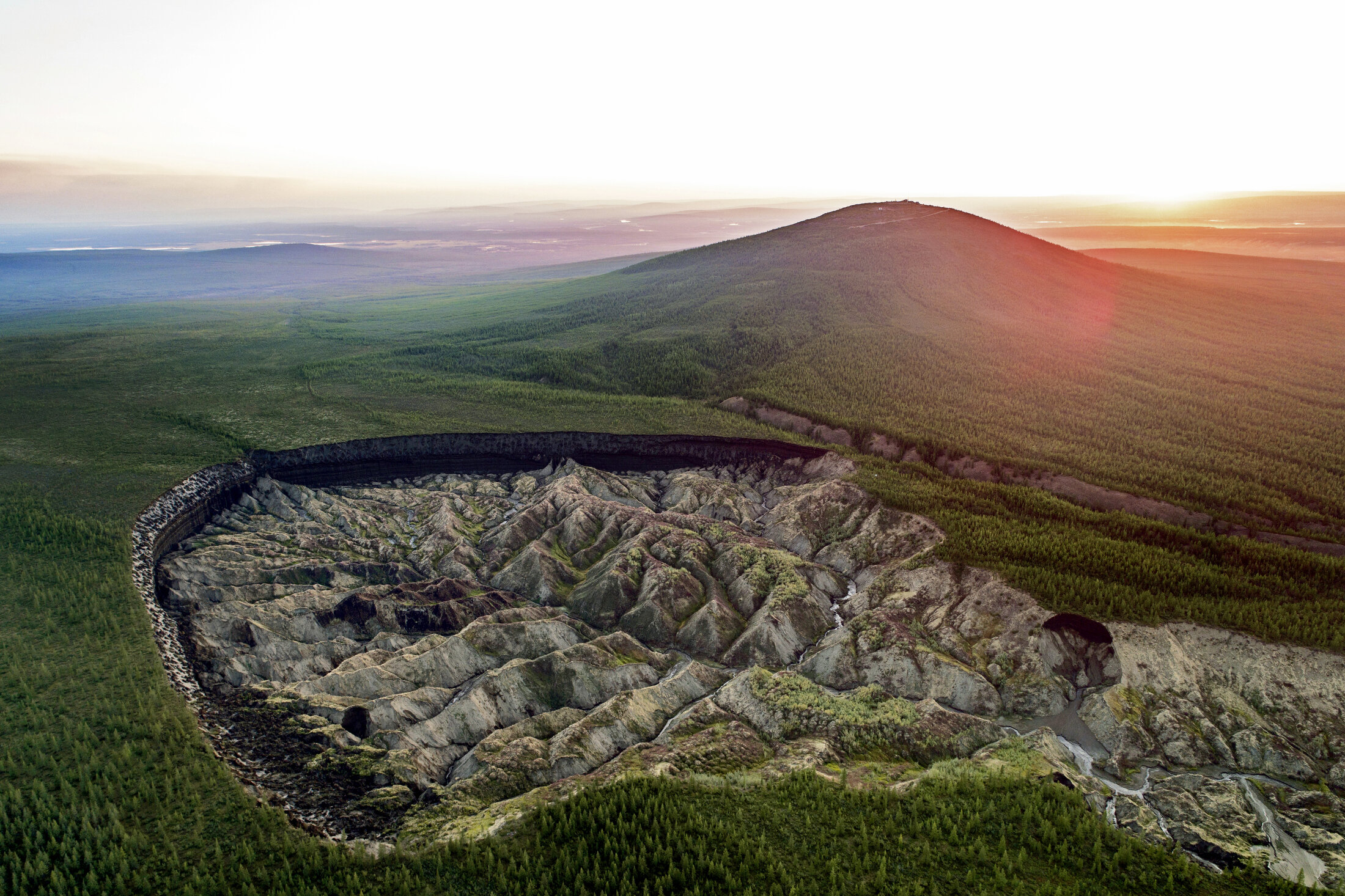  The Batagaika Crater in the Siberian town of Batagay, Russia. It has been called the "hell crater" or the "gateway to the underworld.Ó Over 300 feet deep and 1 kilometer long, this thermokarst depression is one of the biggest in the world, and start