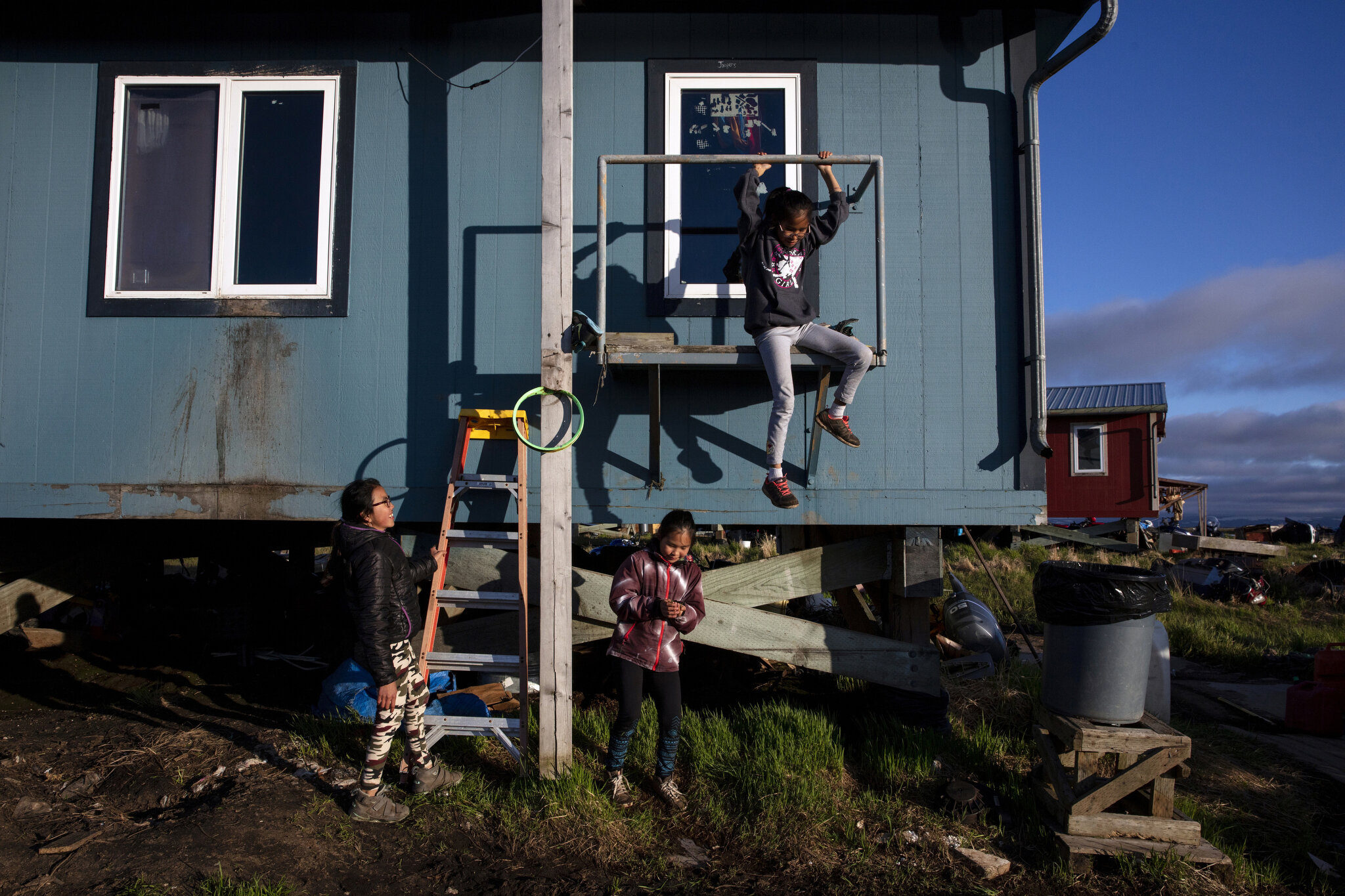  Girls play along outside one of the homes set to be demolished in Newtok, Alaska. May, 2019. Homes rest on pilings in the village of Newtok in western Alaska. This Yupik village (population 380), located along the Ninglik River in the lower Kuskokwi