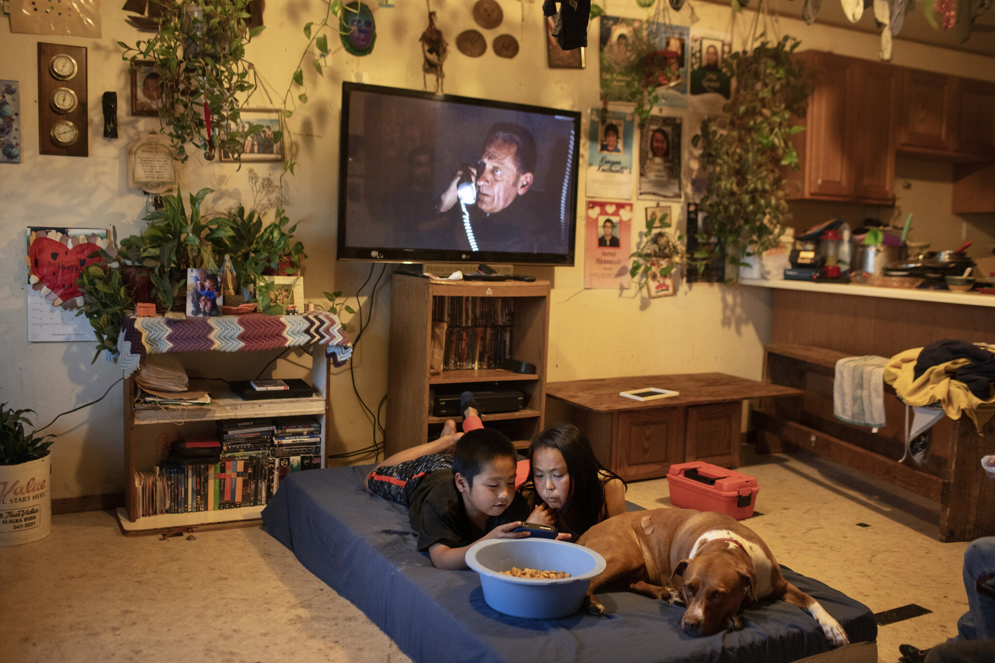  Jasmine and Kenyon Kassaiuli in their living room in Newtok, Alaska. Their ceiling recently split in two as a result of thawing permafrost underneath the ground destroying the house's foundation.  